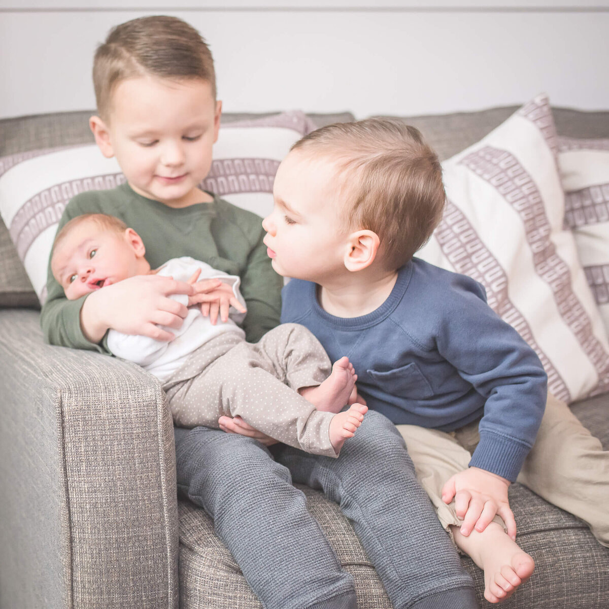 lifestyle newborn and family session big brothers hold new baby brother