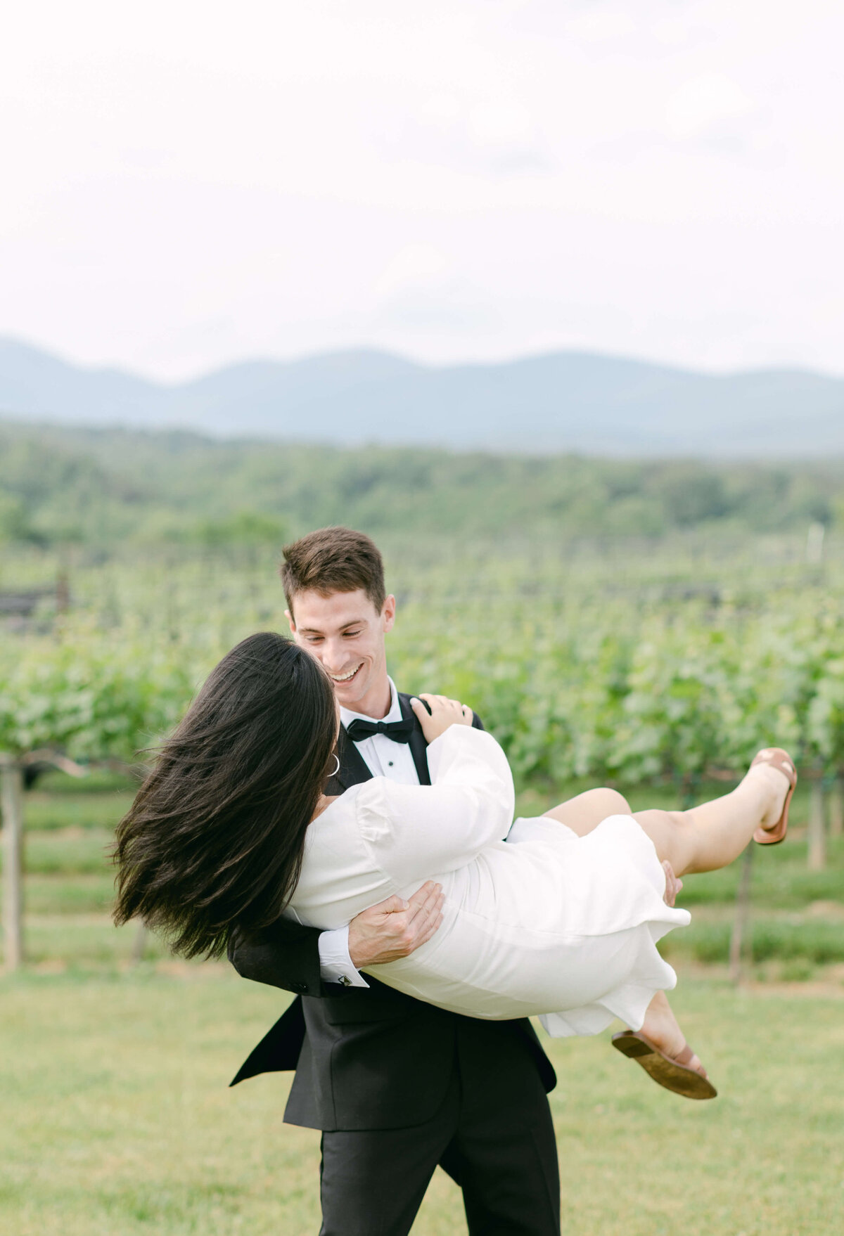 A groom lifts his bride and cradles her in his arms.