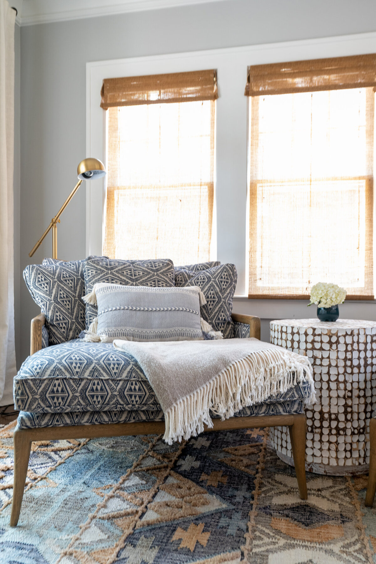 patterned blue oversized chair with pillow blanket lamp and side table