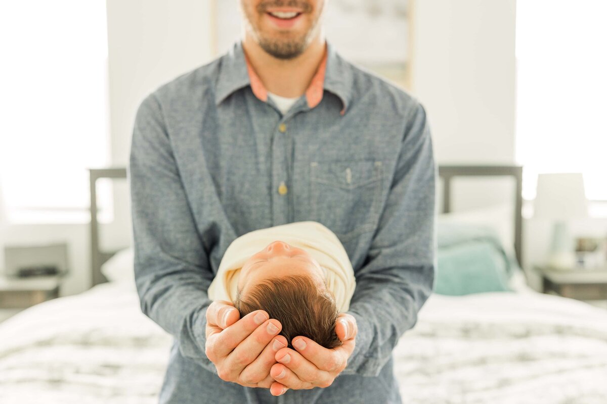 dad holds newborn in hands during lifestyle newborn session