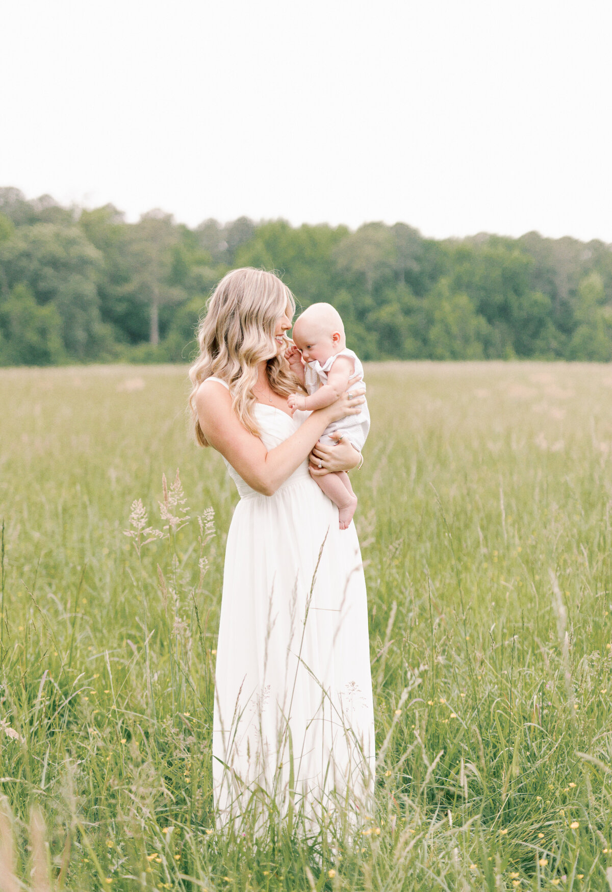 Mom holding baby in a field by Virginia Photographers