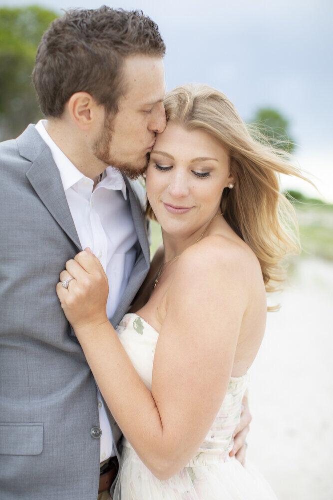 man kisses his fiancée's forehead during engagement session
