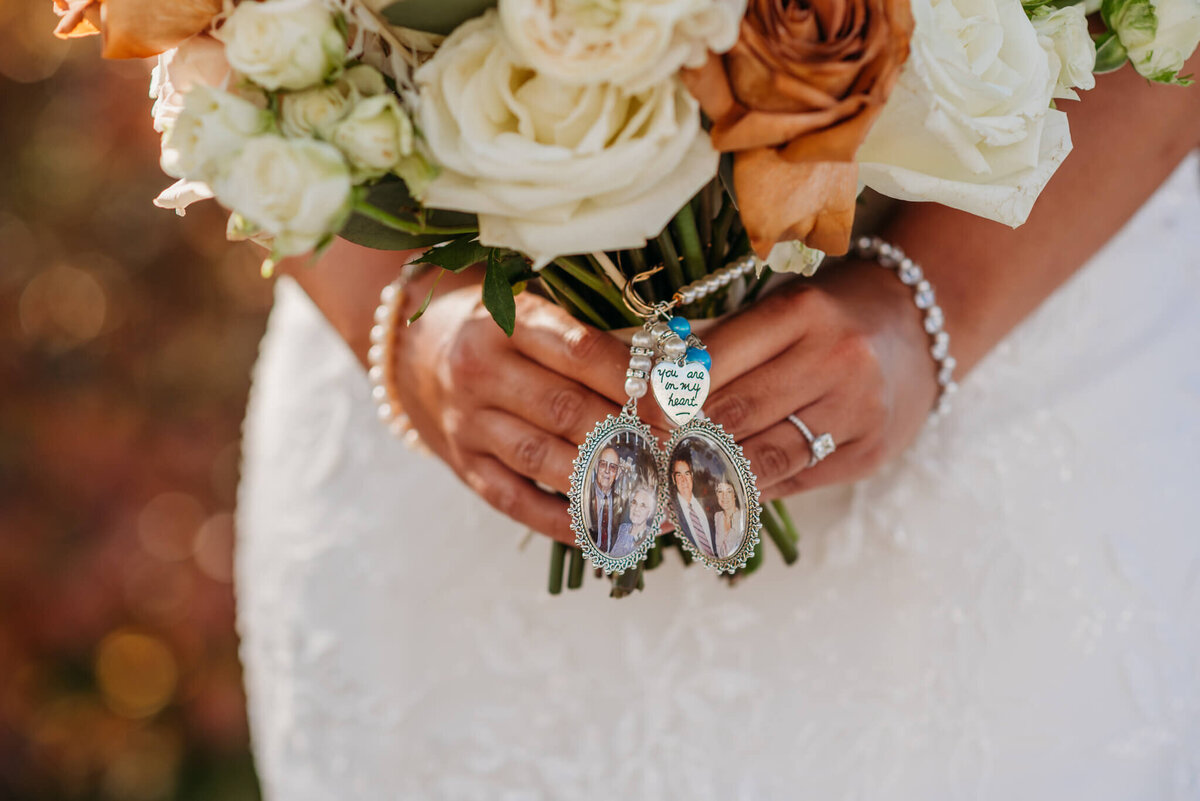 A photo of a charm with small pictures hanging off a bridal bouquet