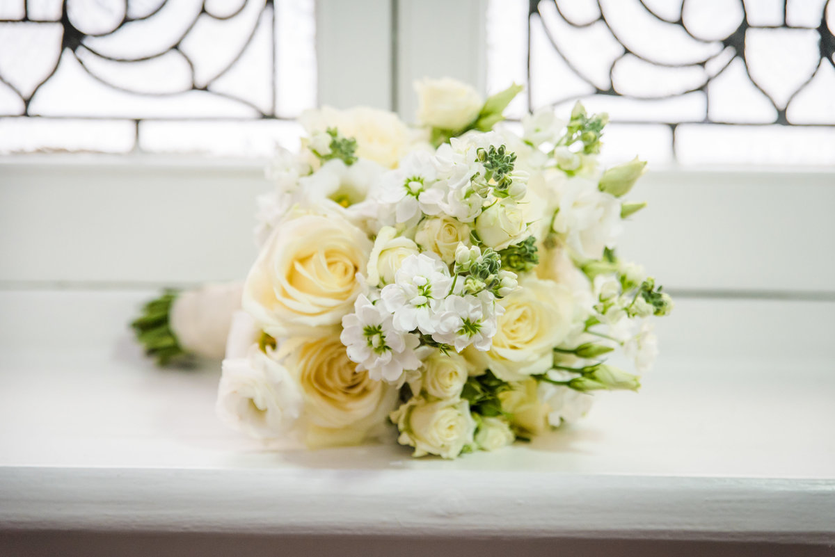 A beautiful white floral bridal bouquet sitting on a windowsill