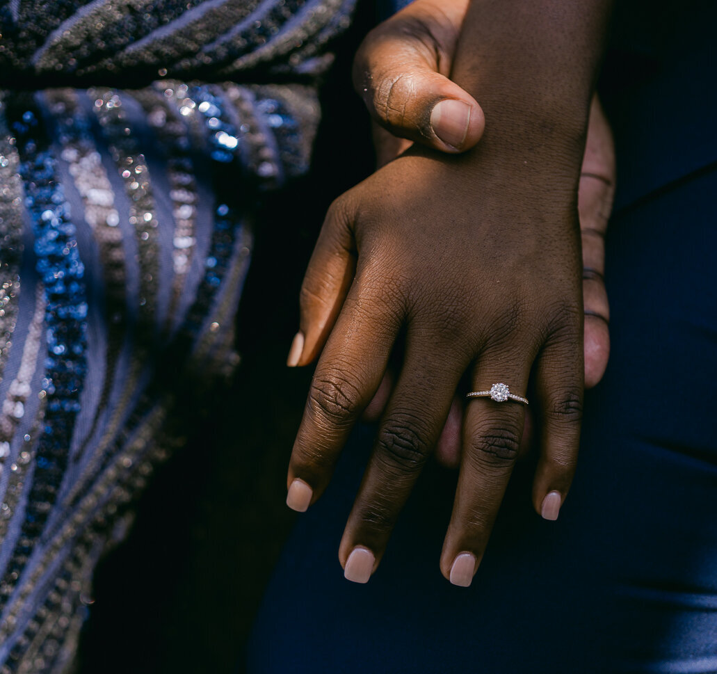 A close up of a ring on a woman's hand as she holds hand with her partner.