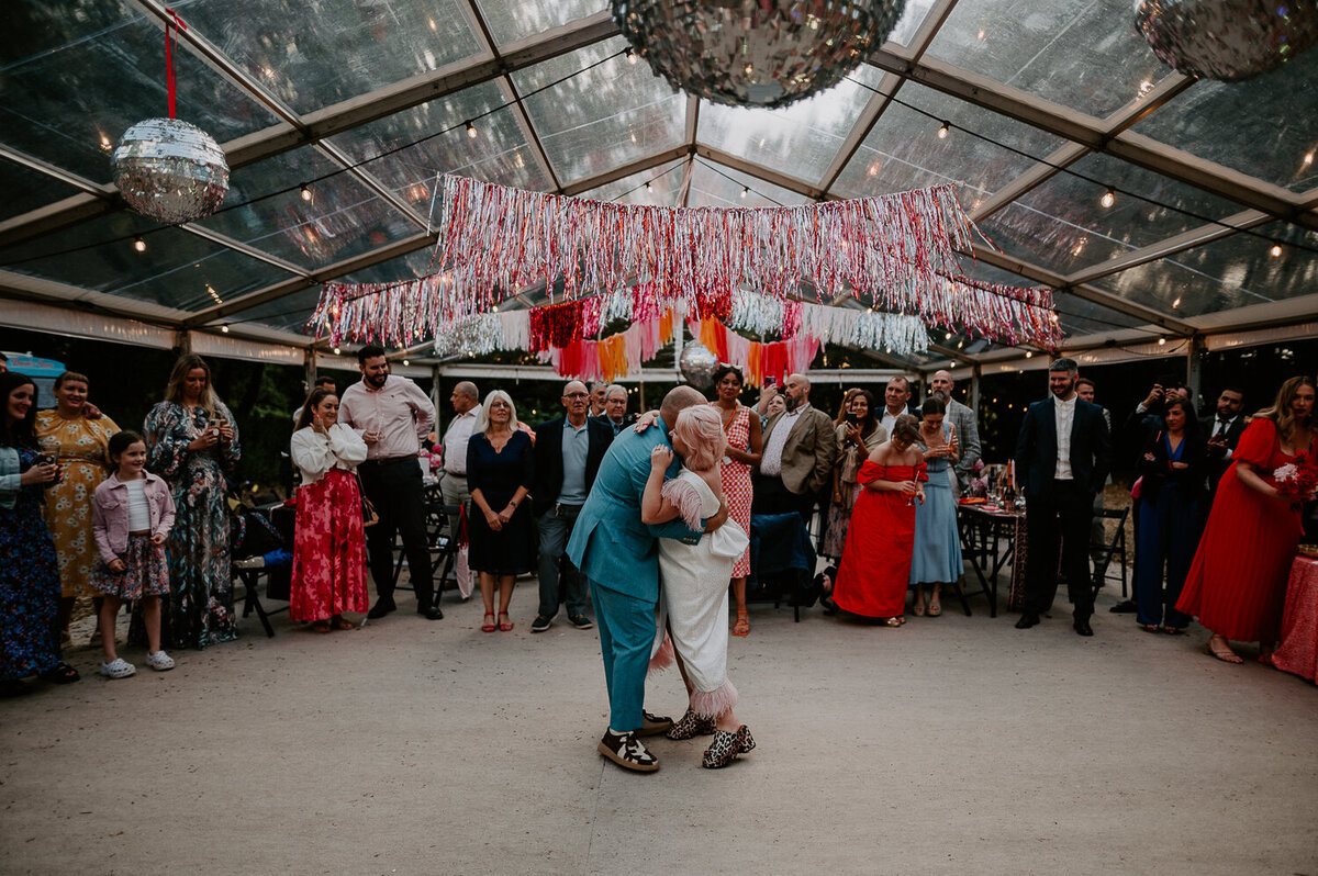Couples first dance under pink streamers and disco ball.