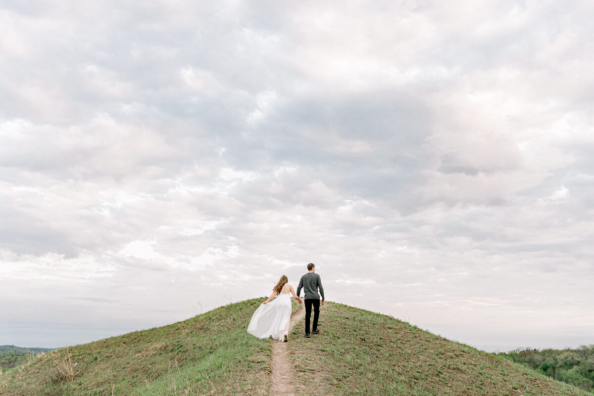 engaged couple walk up a loess hill