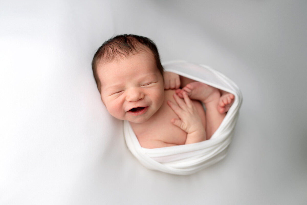 Newborn session of baby boy smiling