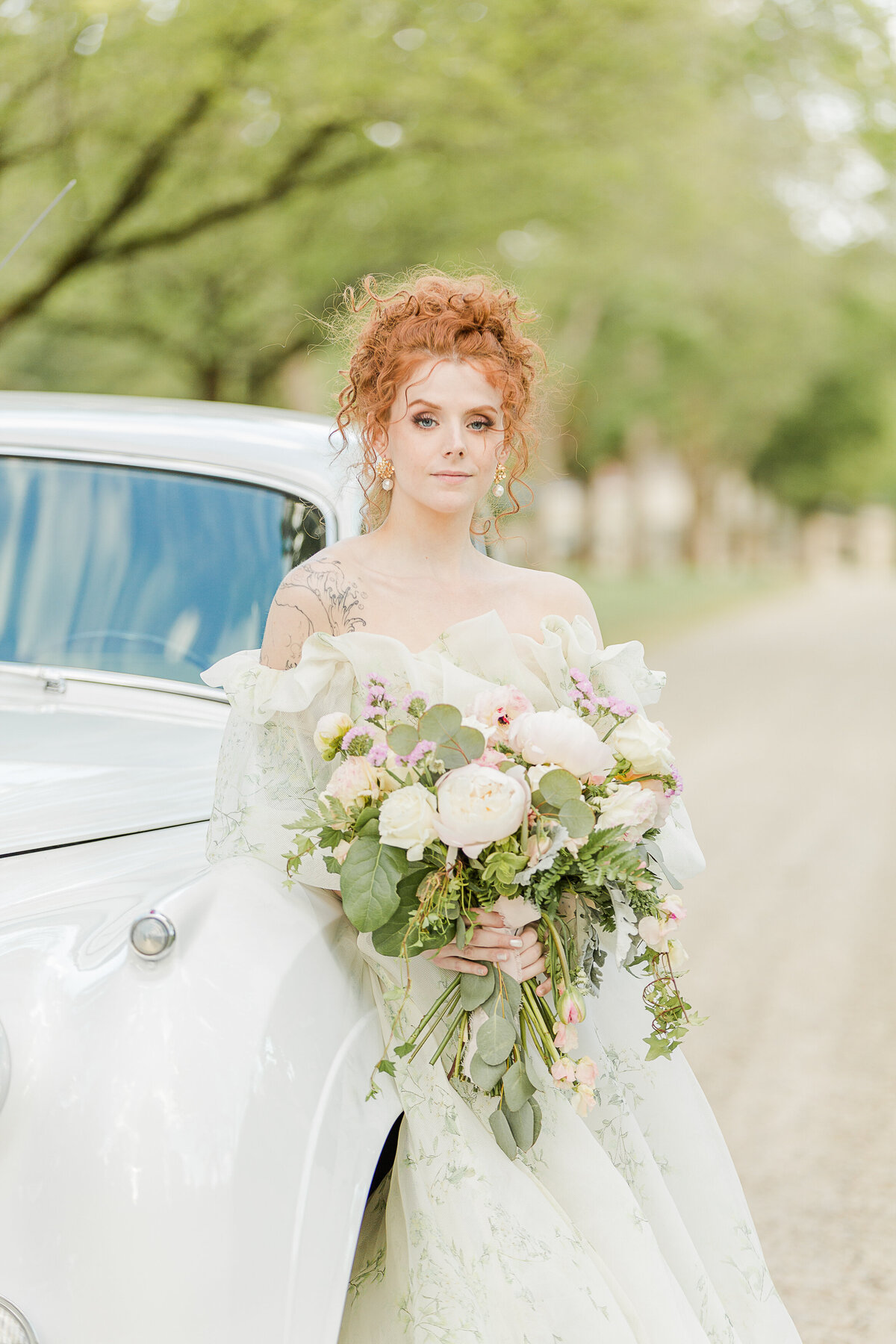 Bride poses against a vintage Rolls Royce for a formal bridal portrait. She is looking intently at the camera. Captured by best Massachusetts wedding photographer Lia Rose Weddings