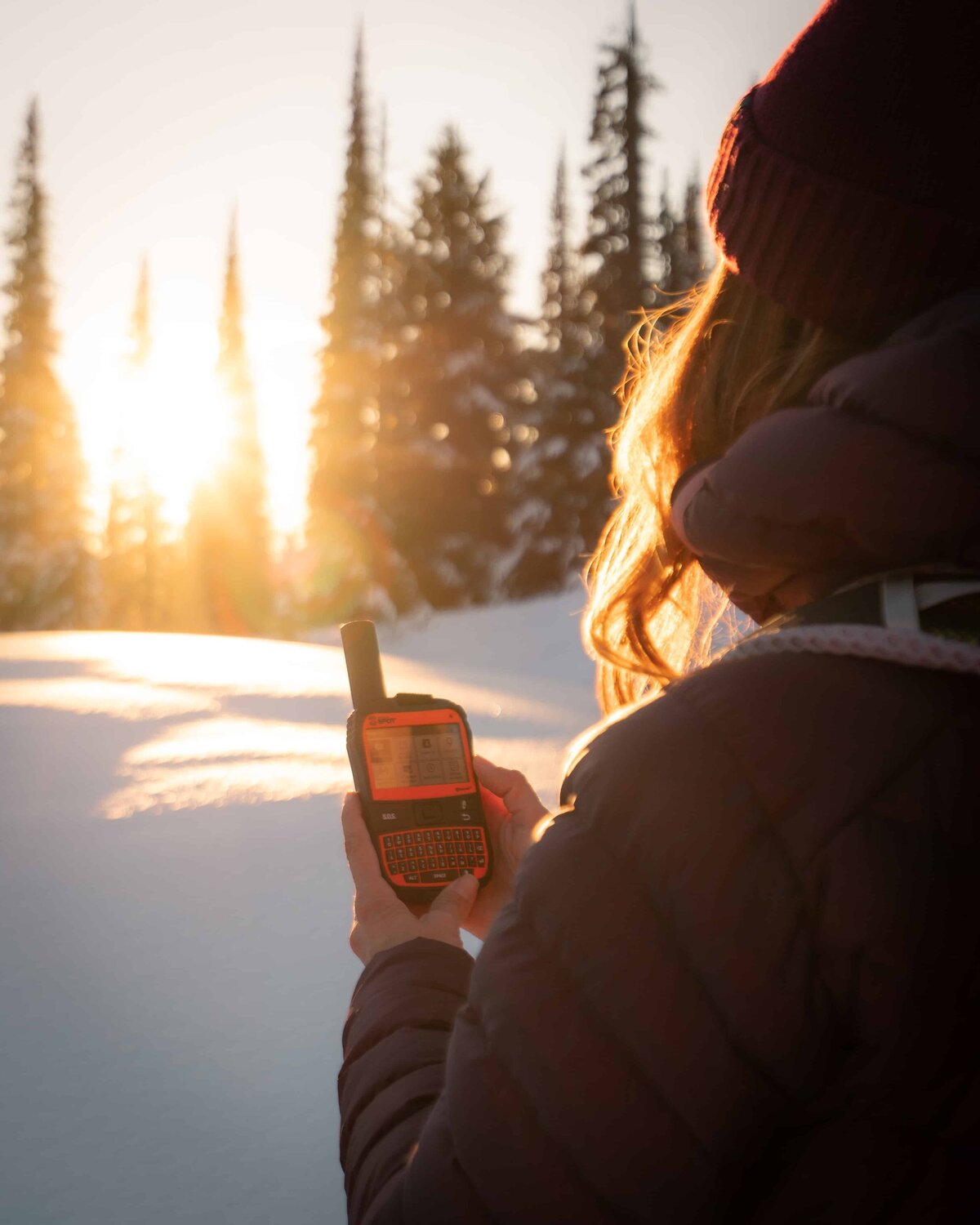 Woman holding an orange SPOT GPS in the snow