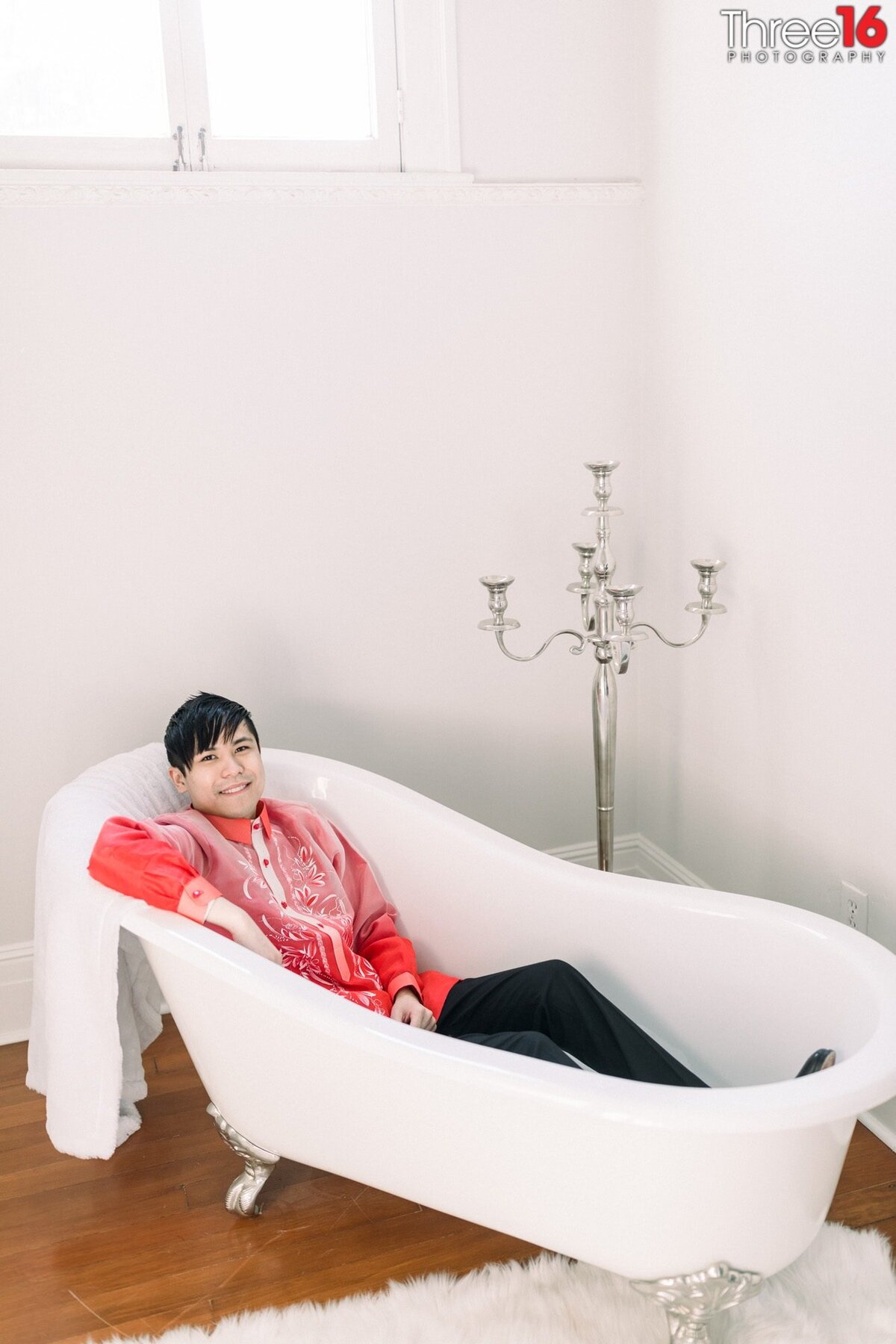 Groom poses while laying in a empty bathtub