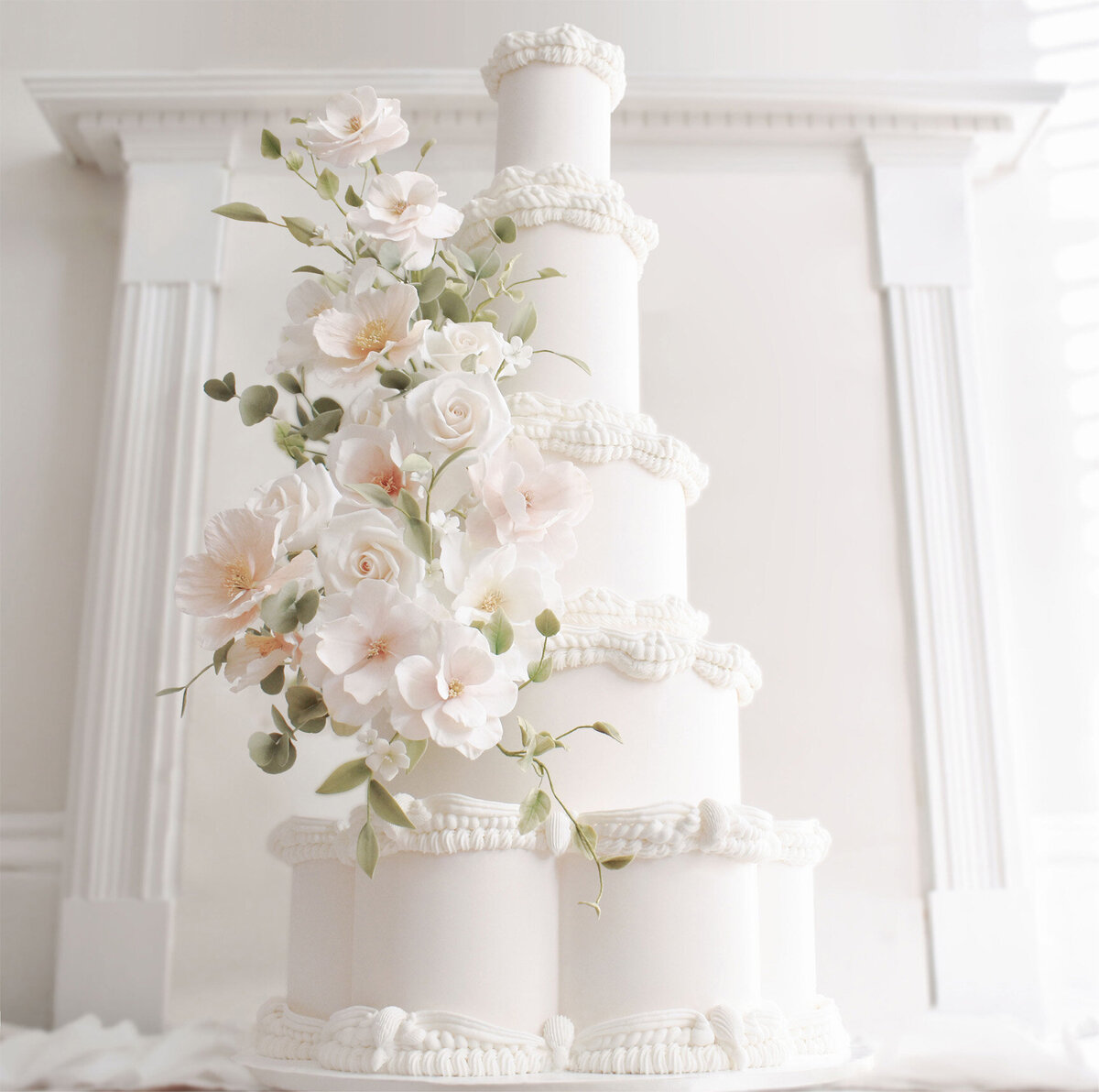 Grand white wedding cake with elegant hand piping and sugar flower cascade