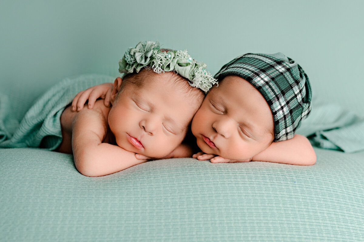 boy girl twins are posed together with boy wearing a hat and gril wearing a headband posed on a teal background