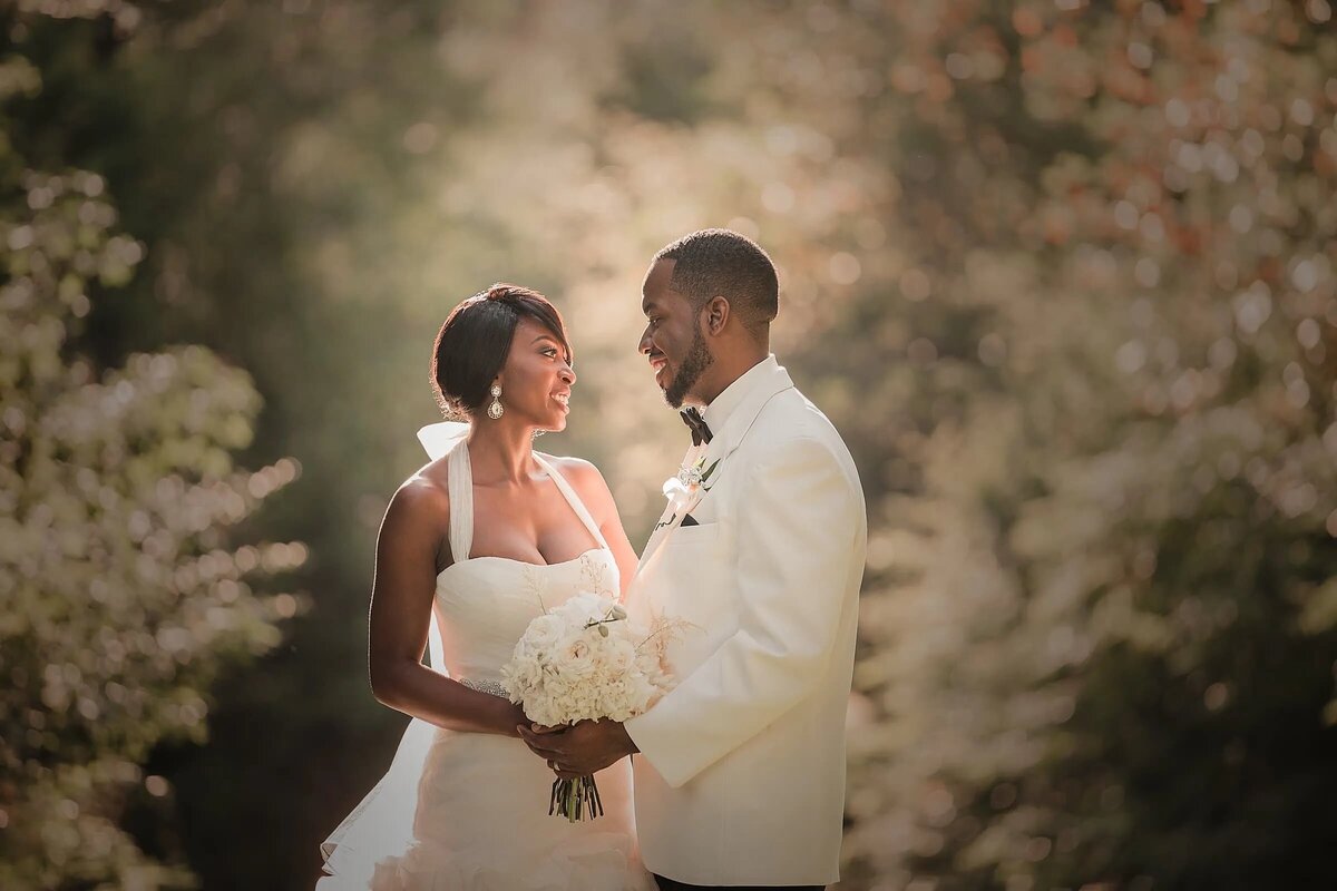A couple shares a loving gaze amidst a backdrop of softly blurred greenery