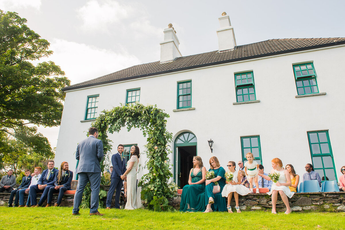 wedding ceremony with floral arch in the garden of Westcove House, Kerry