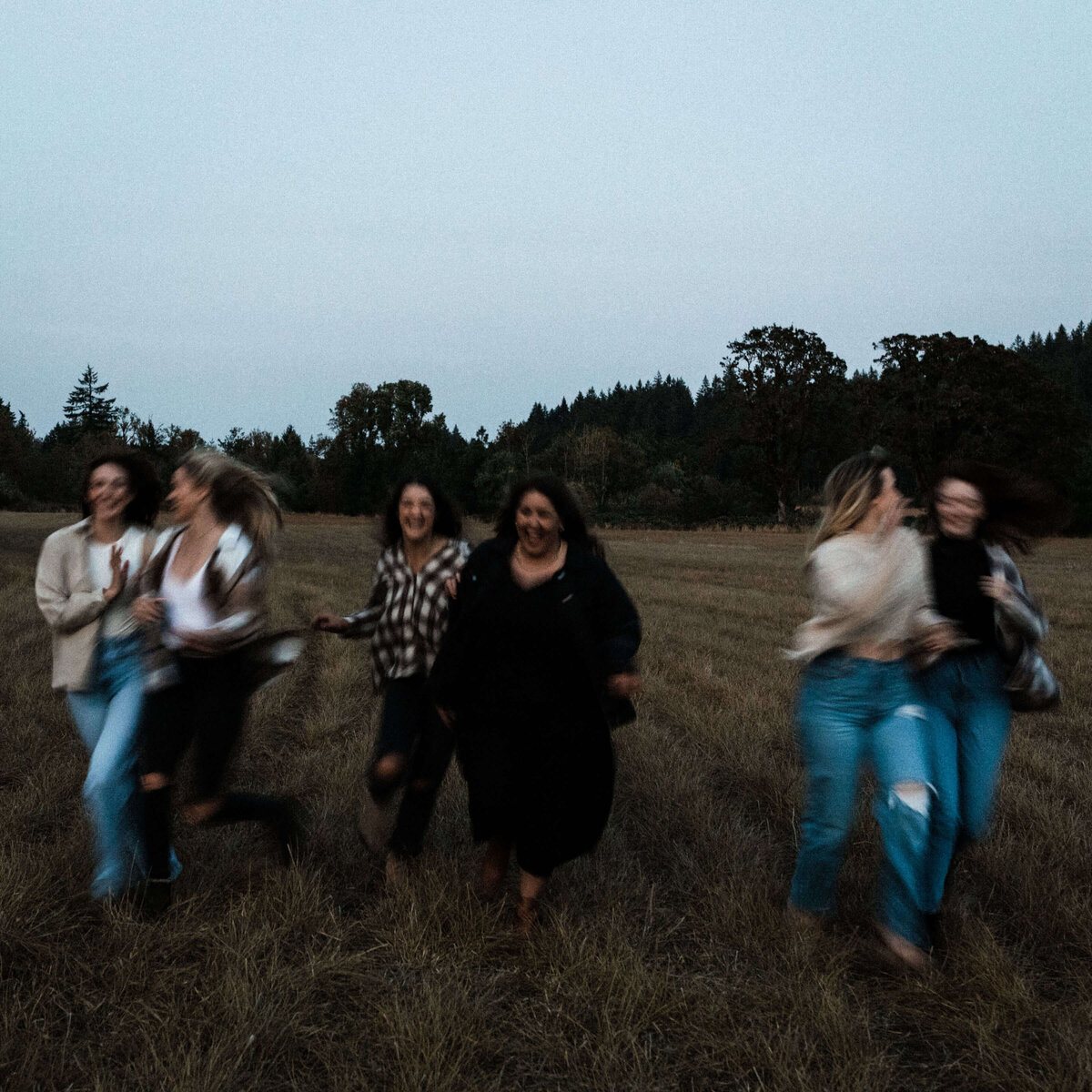 Group of girls run through a field for a motion blurred cinematic photo