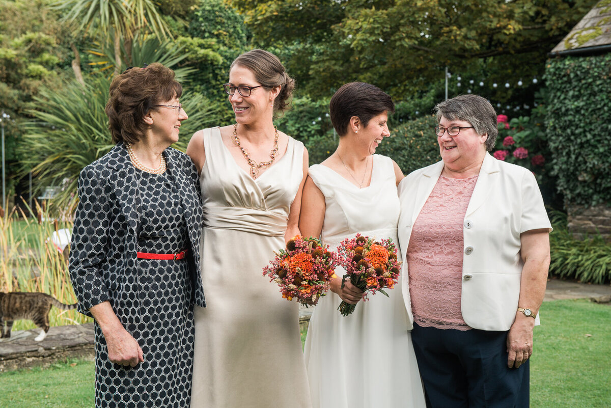Two brides laughing with their mums in the garden