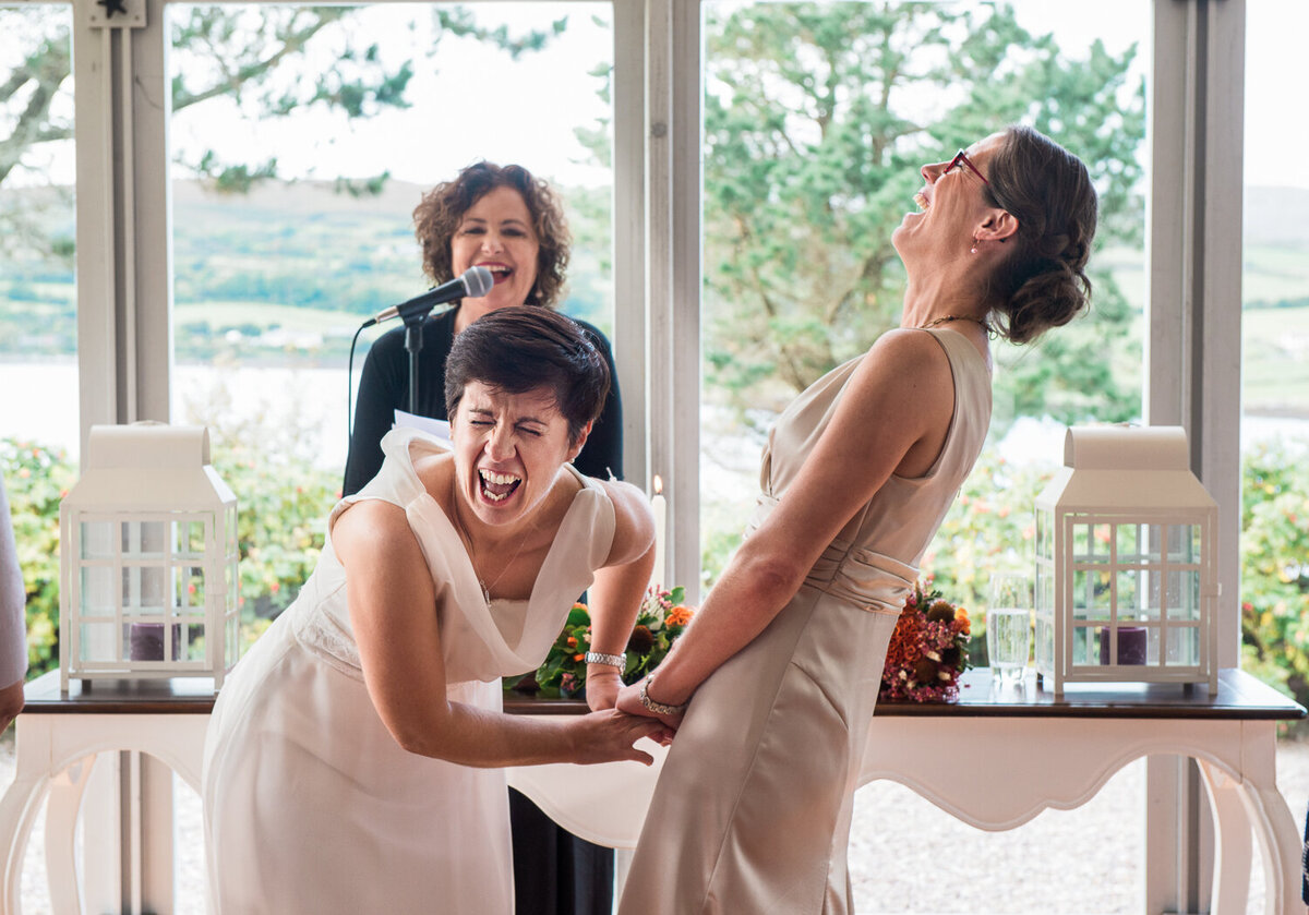 Two brides at their wedding ceremony, laughing out loud