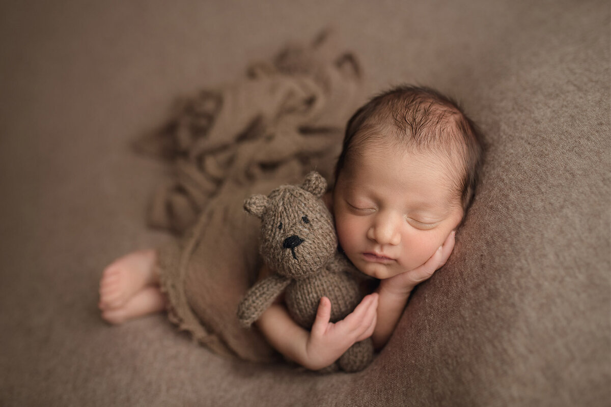 Sleeping newborn holding teddy bear during boston newborn session