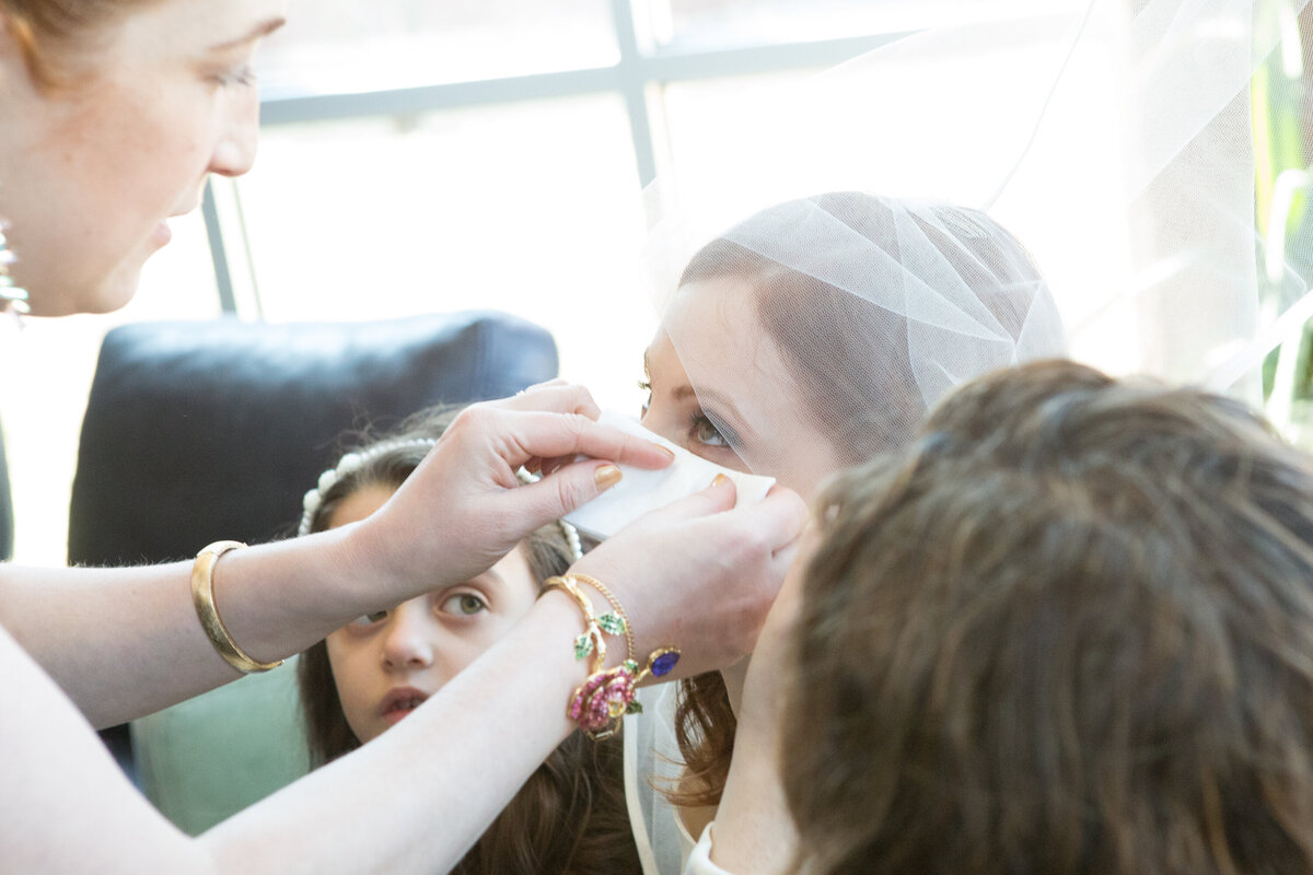 Close up of a bridesmaid wiping away a bride's happy tears New York Modern Orthodox Jewish wedding photographer Milestone Images