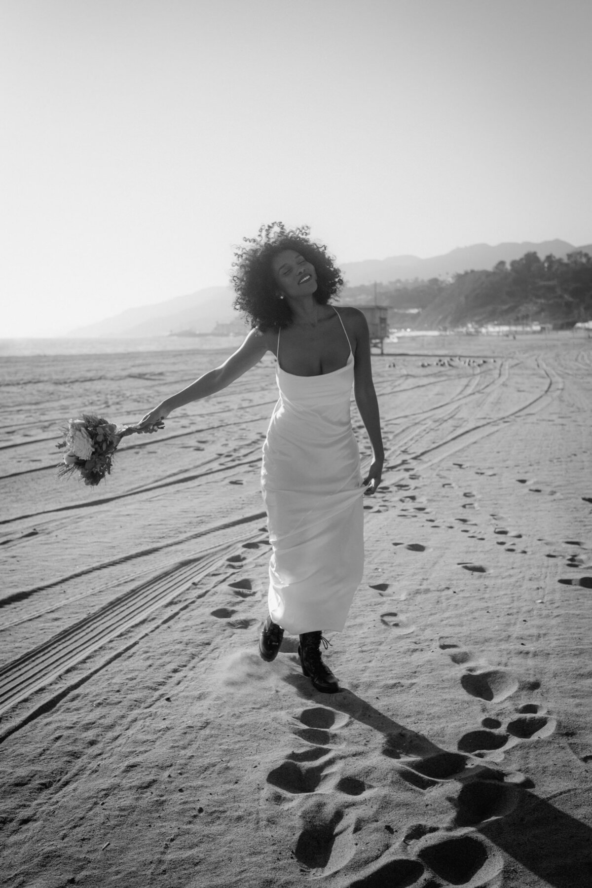 Mit dem Wind im Haar läuft die Braut über den Sand.