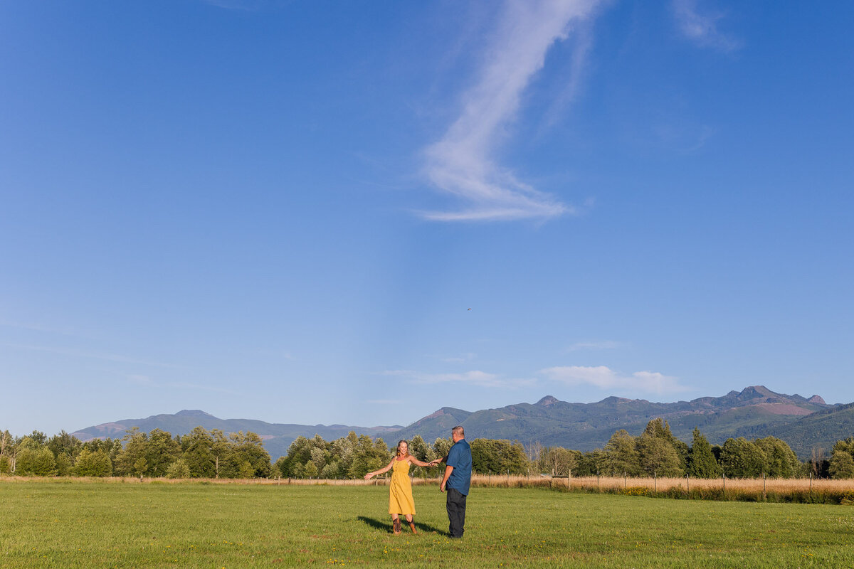 Epic summer engagement session in fields with blue Skagit county near Belliingham happy couple dancing candid colorful photo by Joanna Monger Photography