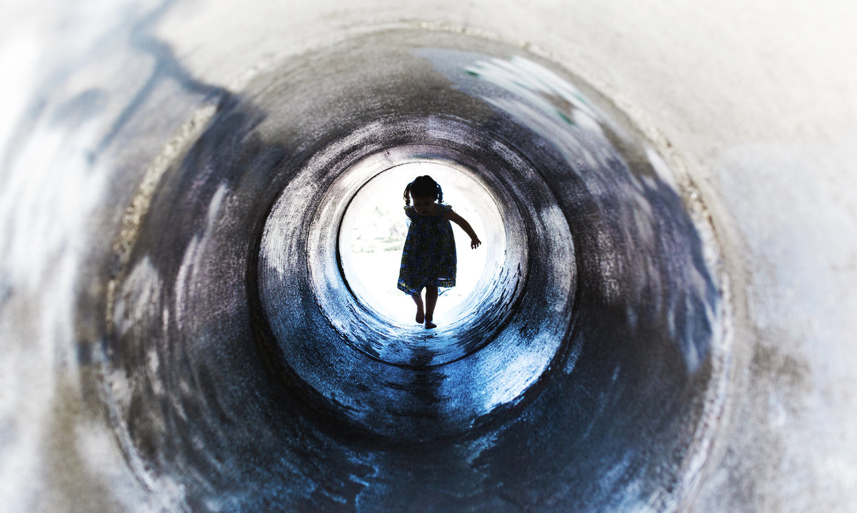 charlotte documentary photographer jamie lucido captures a beautiful and artistic silhouette of a child coming through a tunnel at a playground, Dennis the Menace in Monterey, California