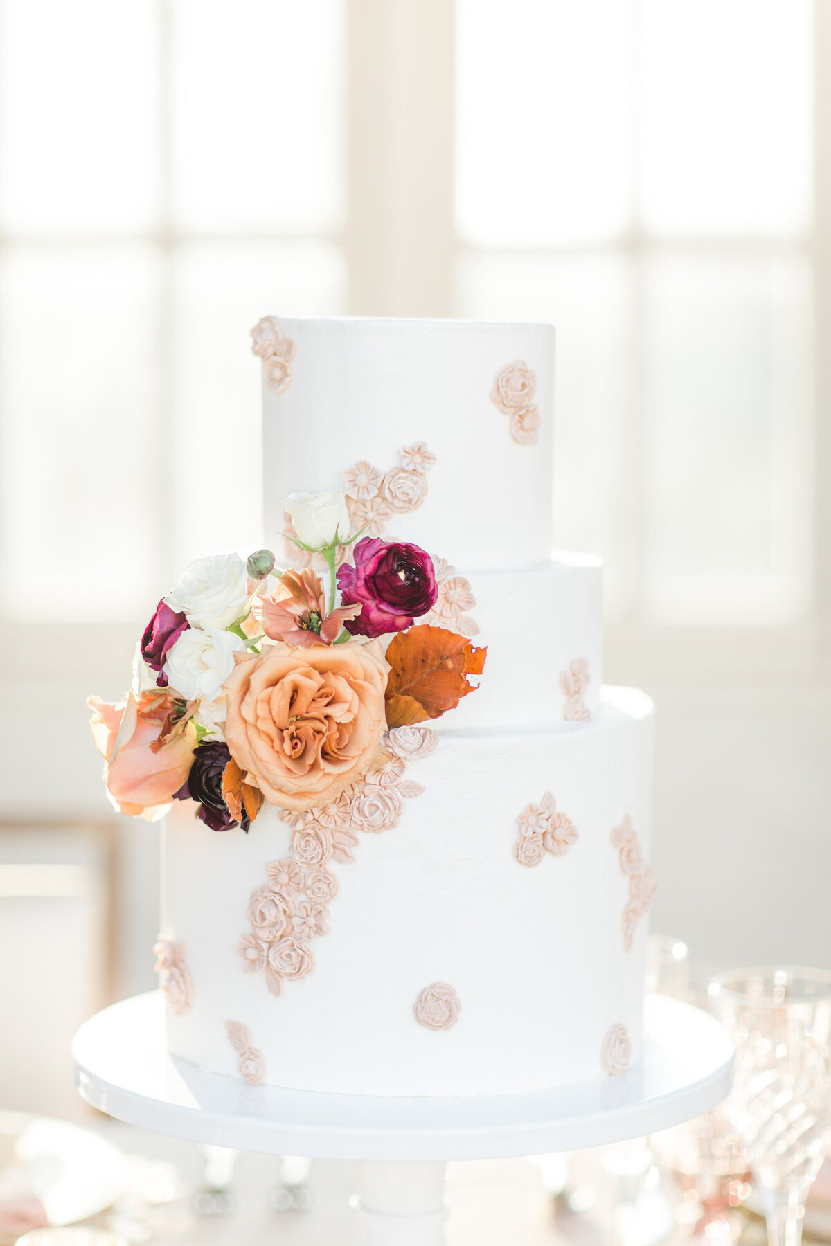 Wedding cake with lace motifs and pink and orange flowers