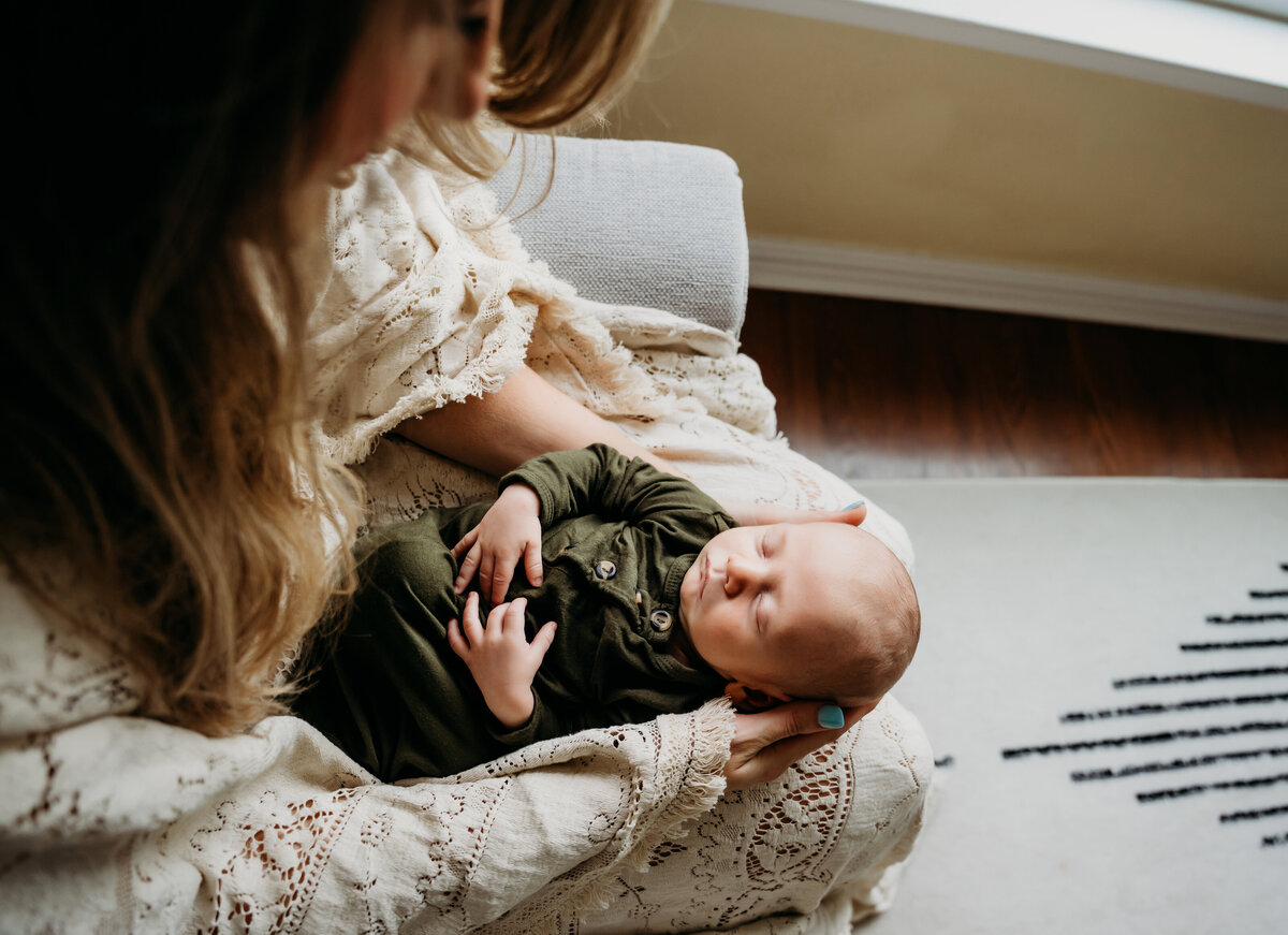 Newborn Photographer, a mother sits with her new baby boy in her lap