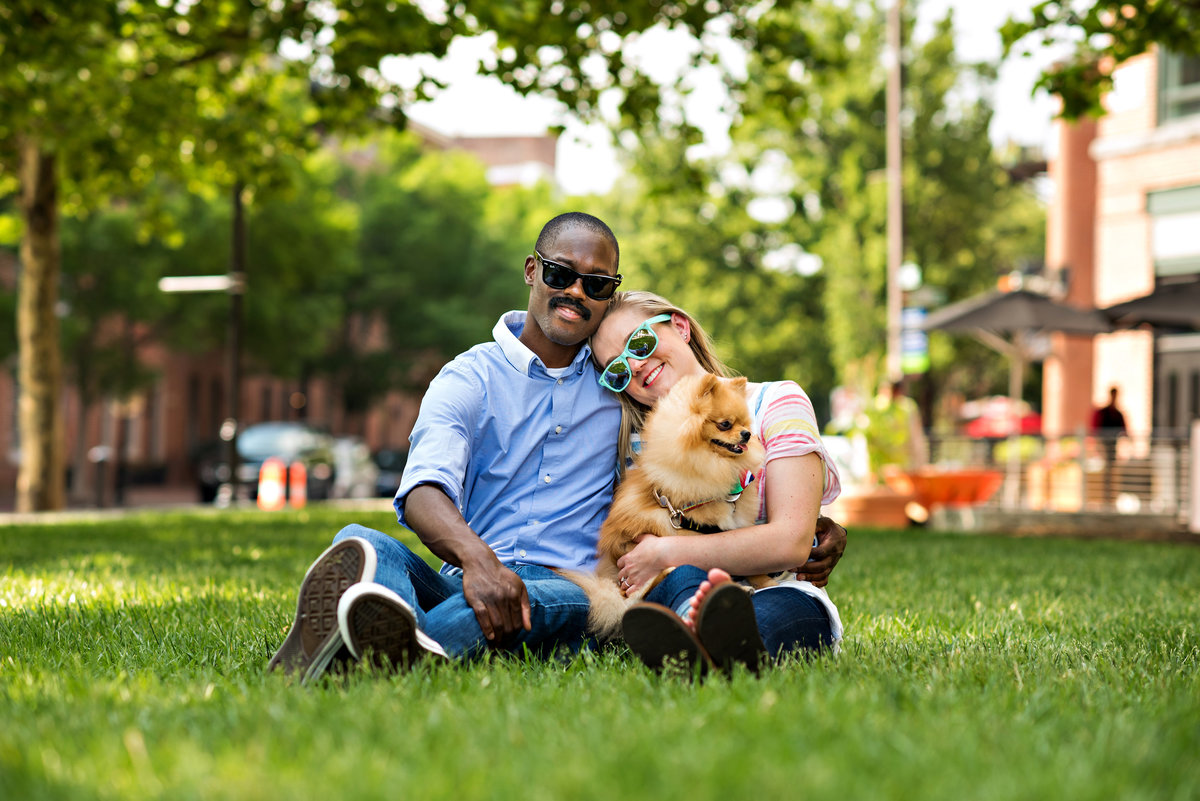 A couple lay in the park with their dog on a beautiful summer day.