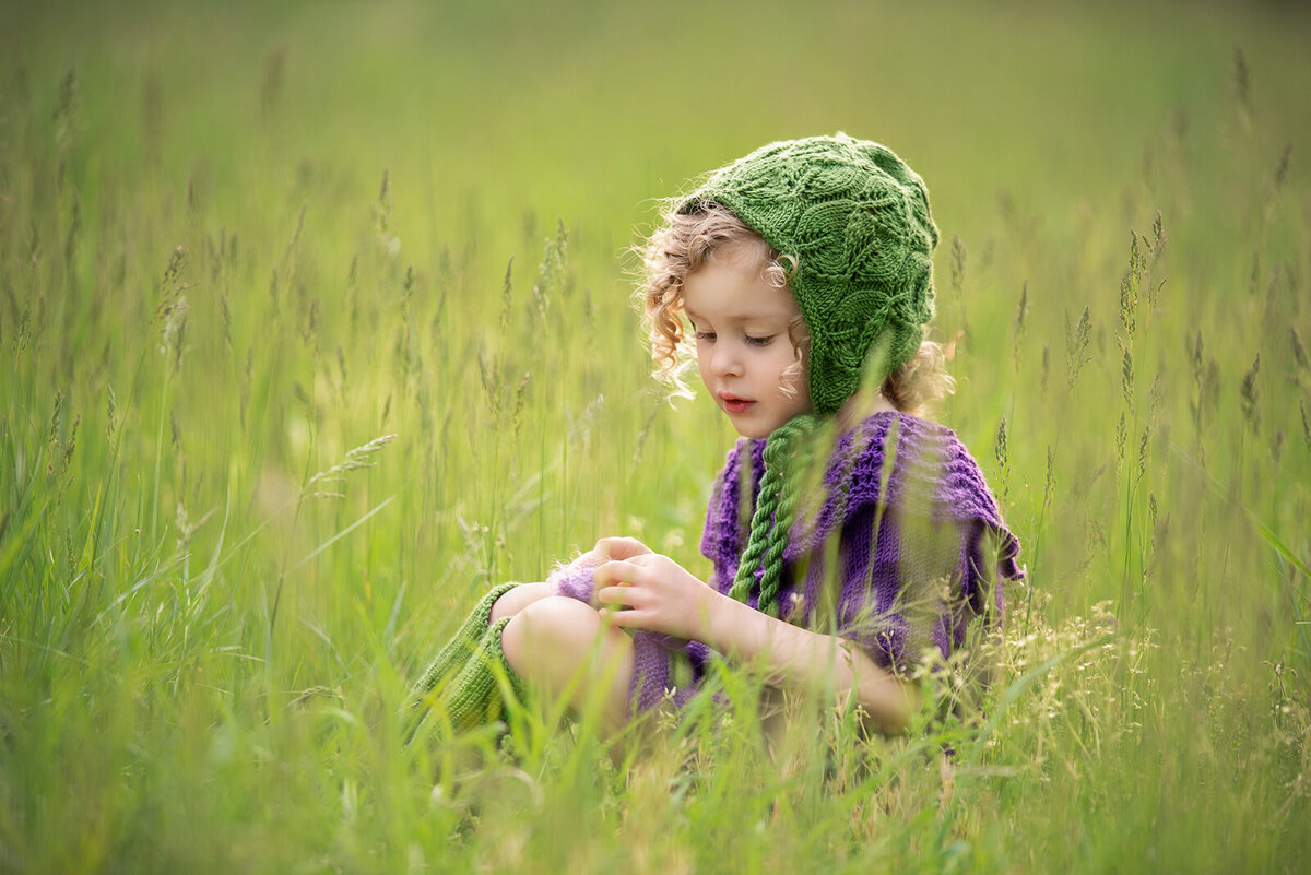 girl playing with purple bear in a field
