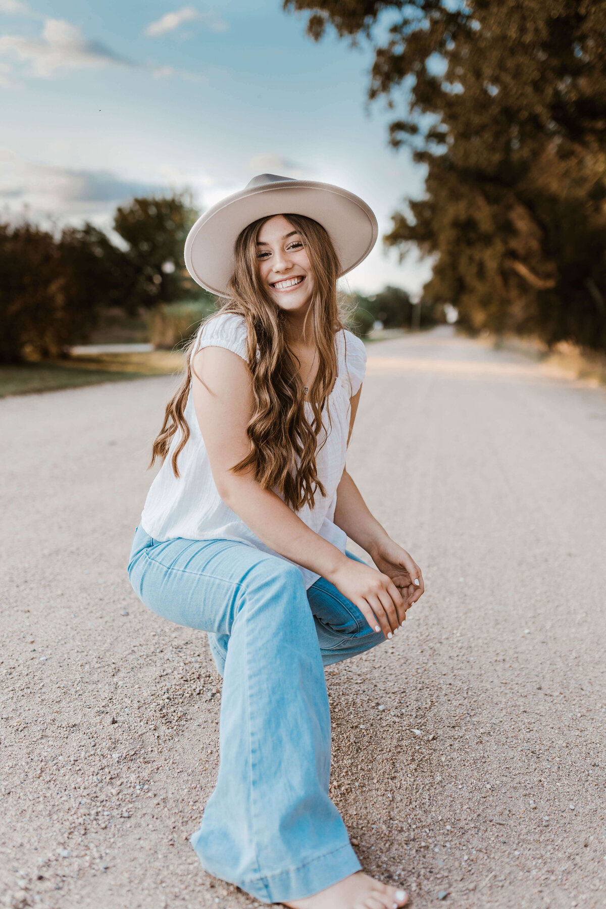 Senior posing on a gravel road barefoot