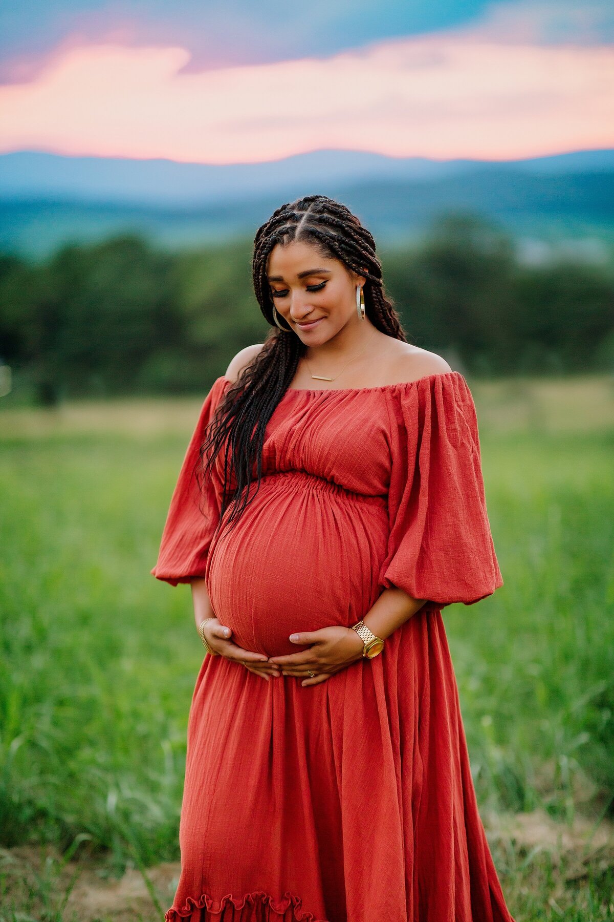 Pregnant mom in red gown at sunset with mountain view