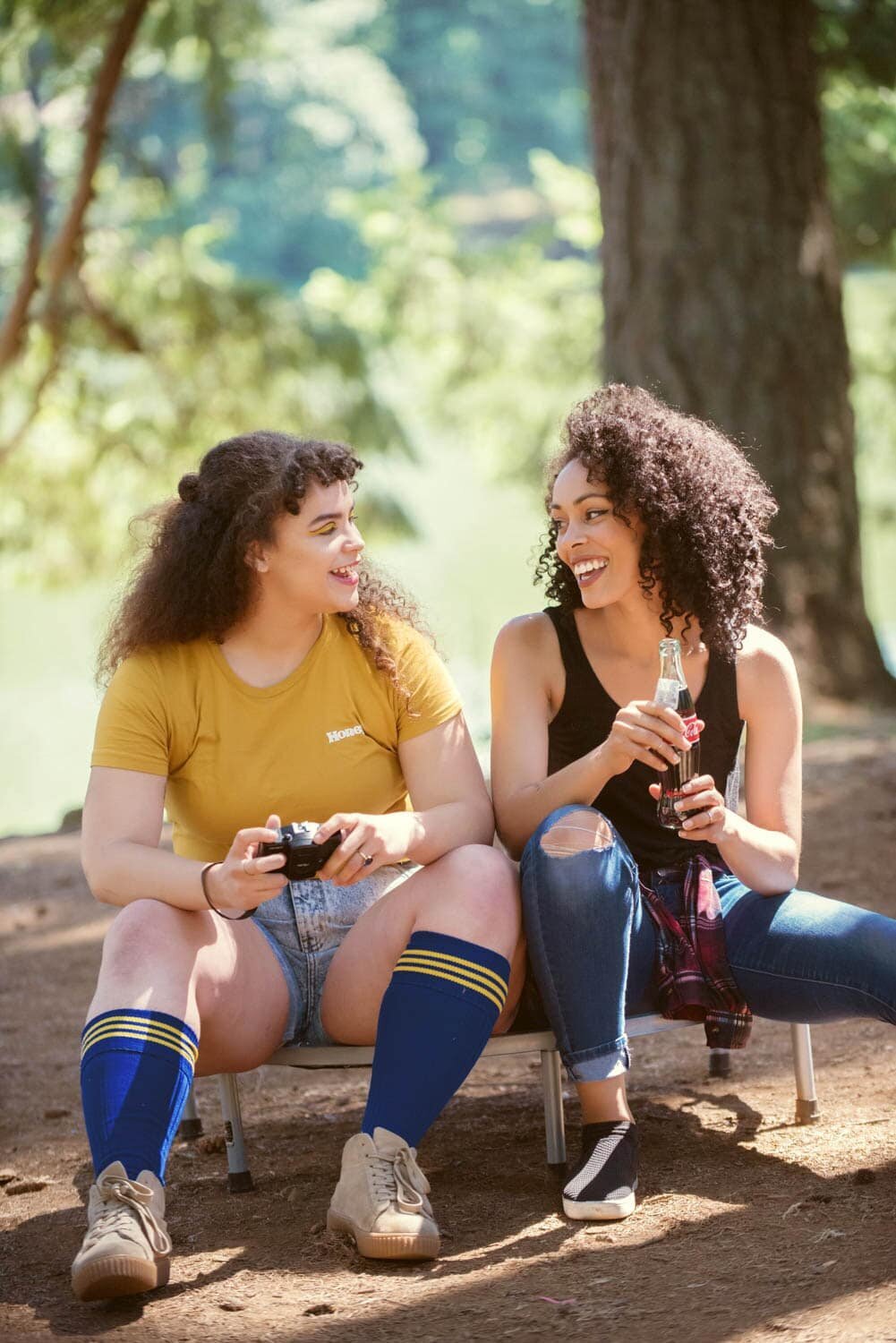 two girls dressed for 80s summer camp sit and talk