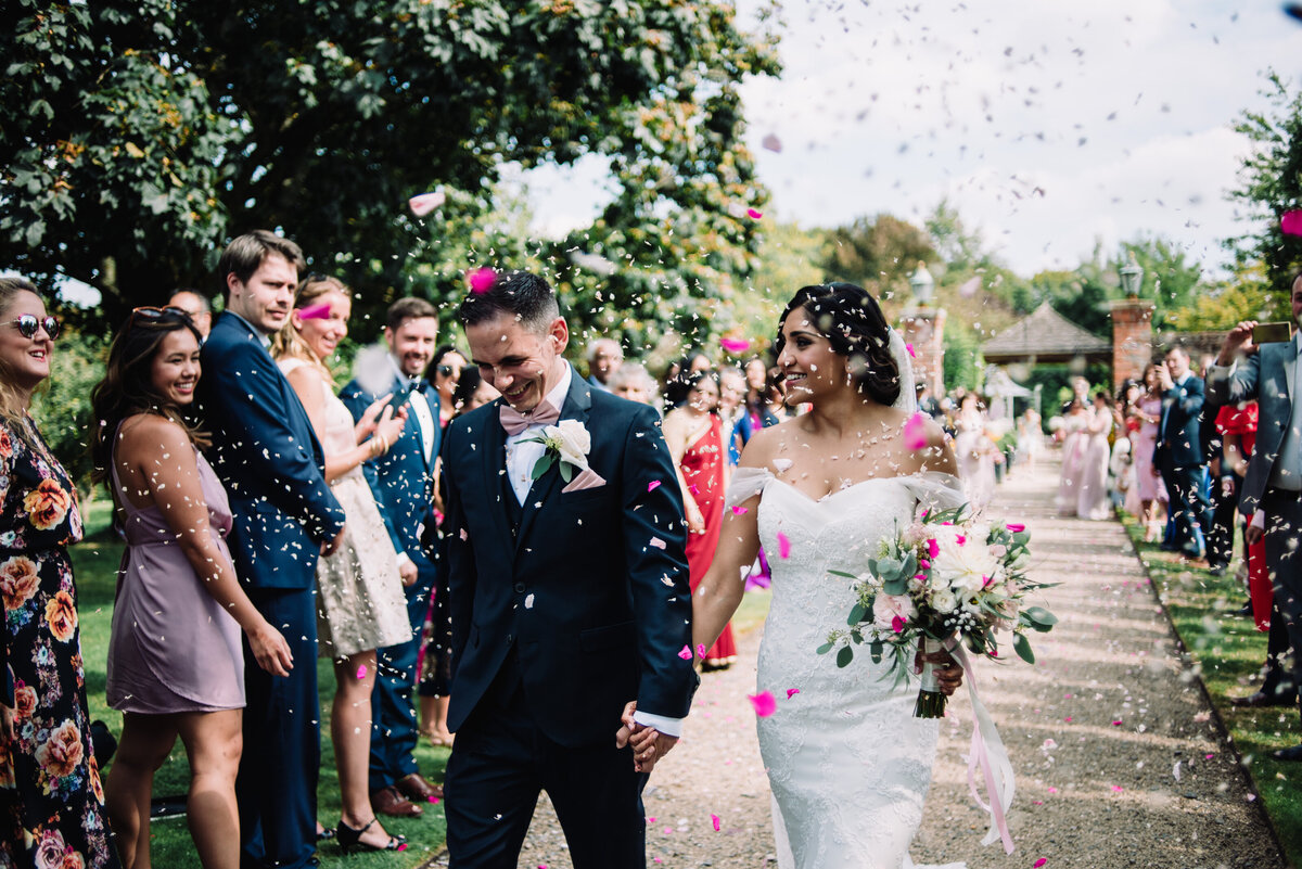 A couple walking down the aisle covered in confetti taken by London Wedding Photographer Liberty Pearl