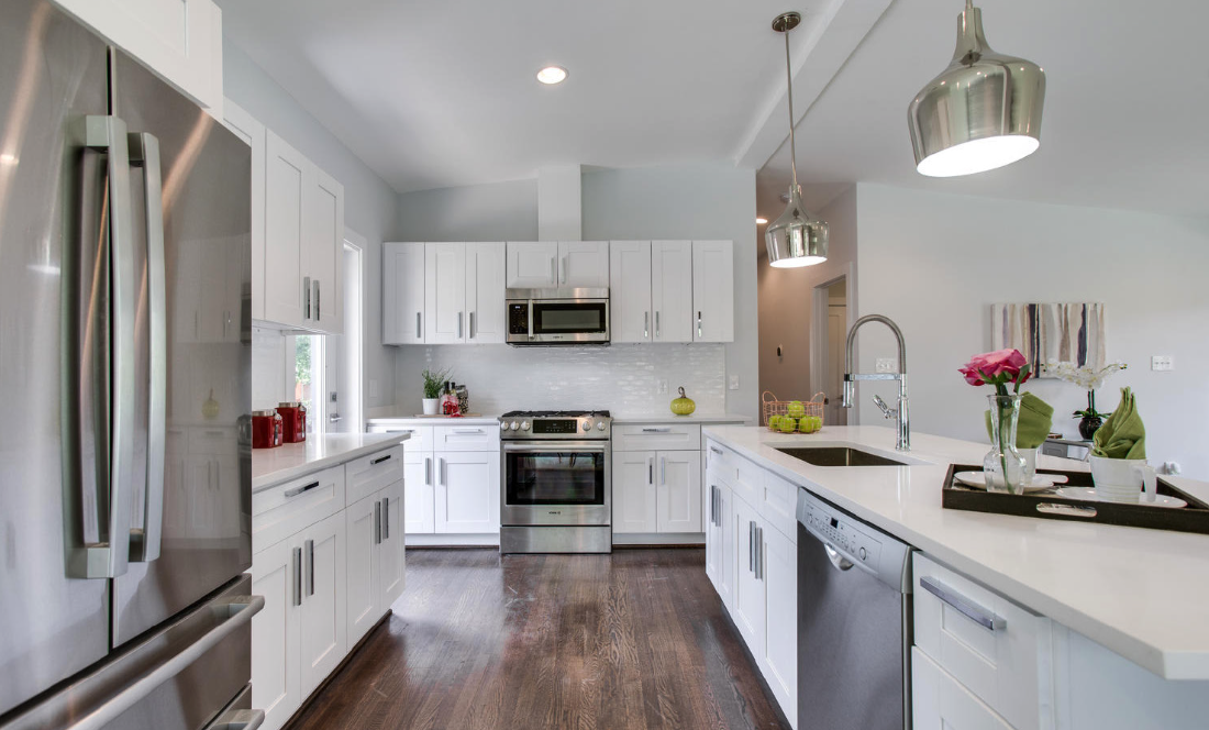 Clean modern kitchen redesign with white cabinets and hardwood floors.