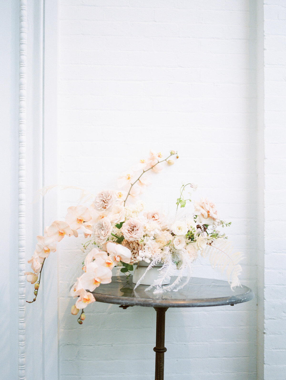 A large, pink floral bouquet sits on a table in front of a white brick wall by Huntsville wedding photographer, Kelsey Dawn Photography