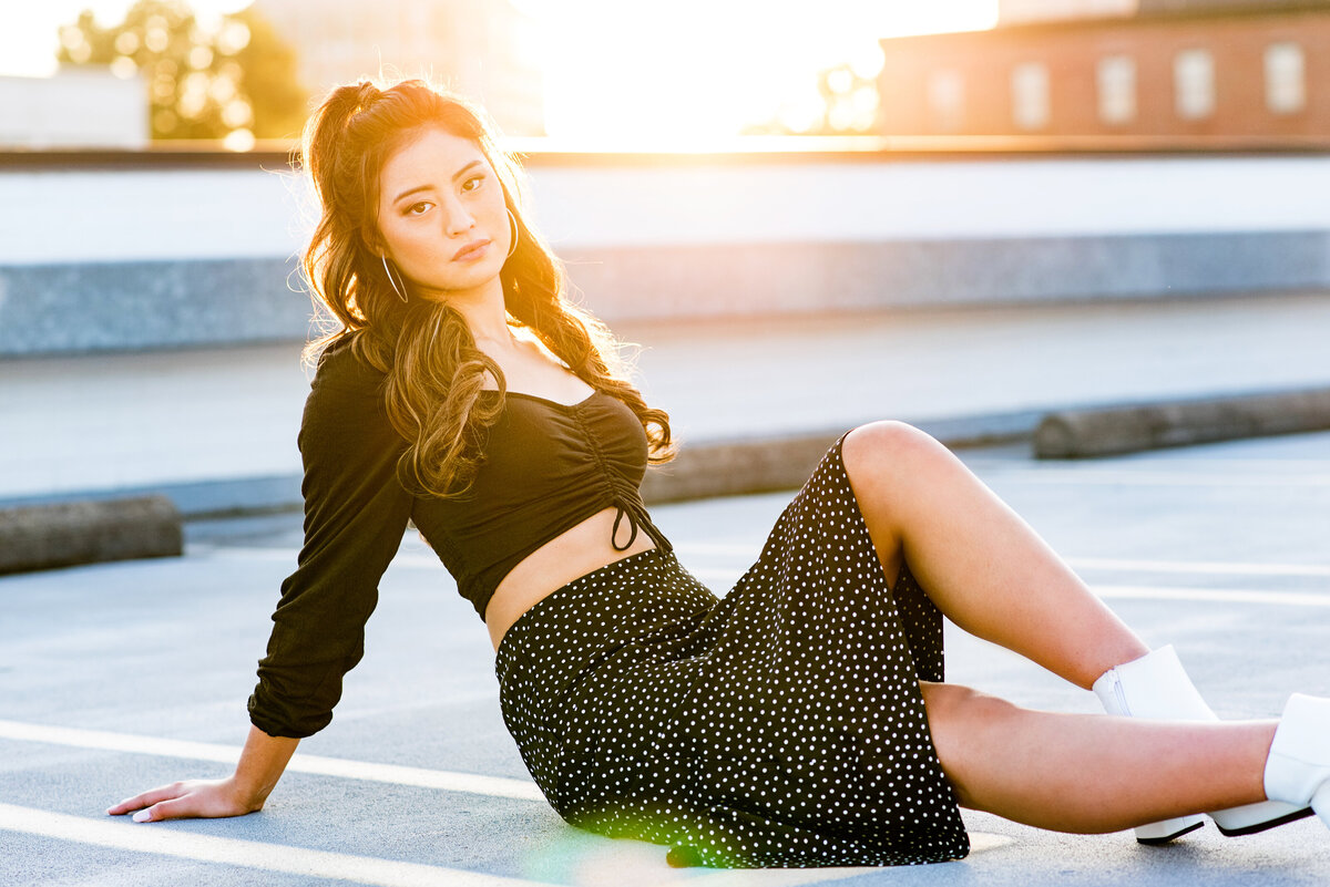 Senior girl sitting on rooftop at sunset with sunflare .