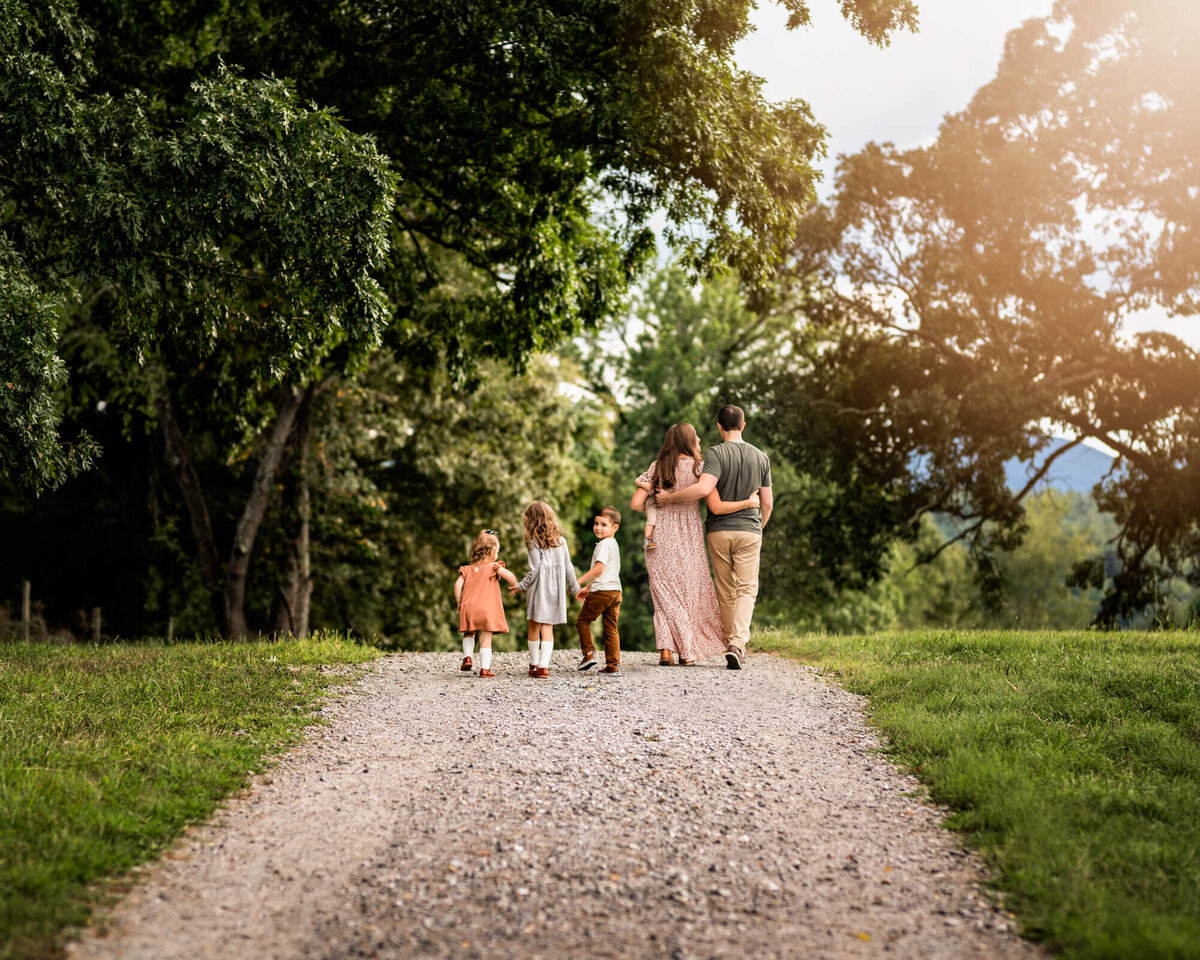 A family of six walking down a gravel path during their photo session with an Asheville Family Photographer