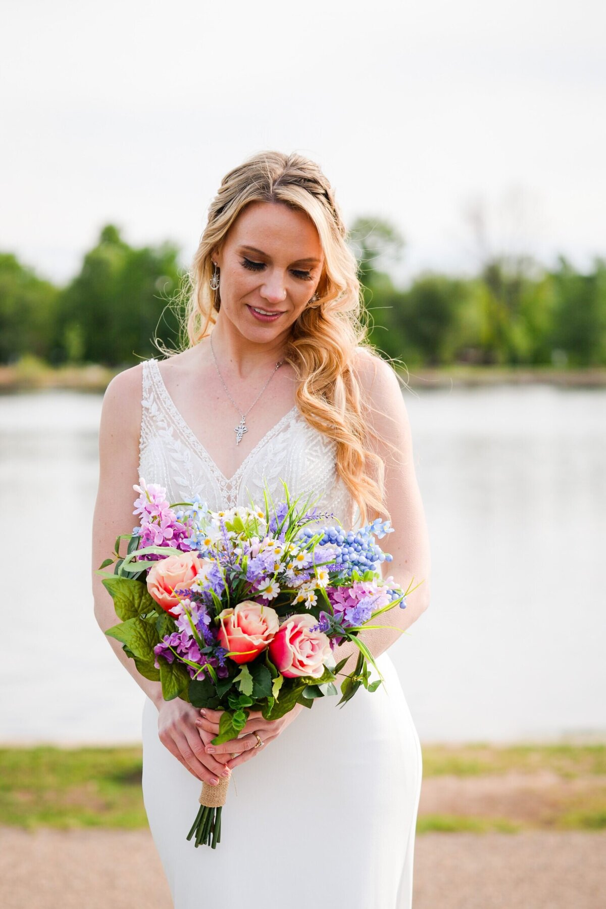 A bride looks down at her vibrant colored bouquet.