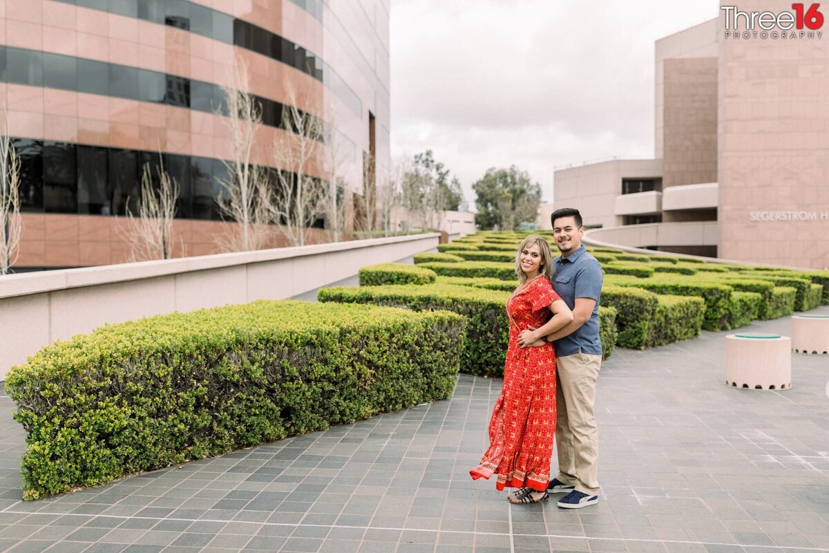 Groom to be holds his Bride from behind for photos at the Segerstrom Center for the Arts