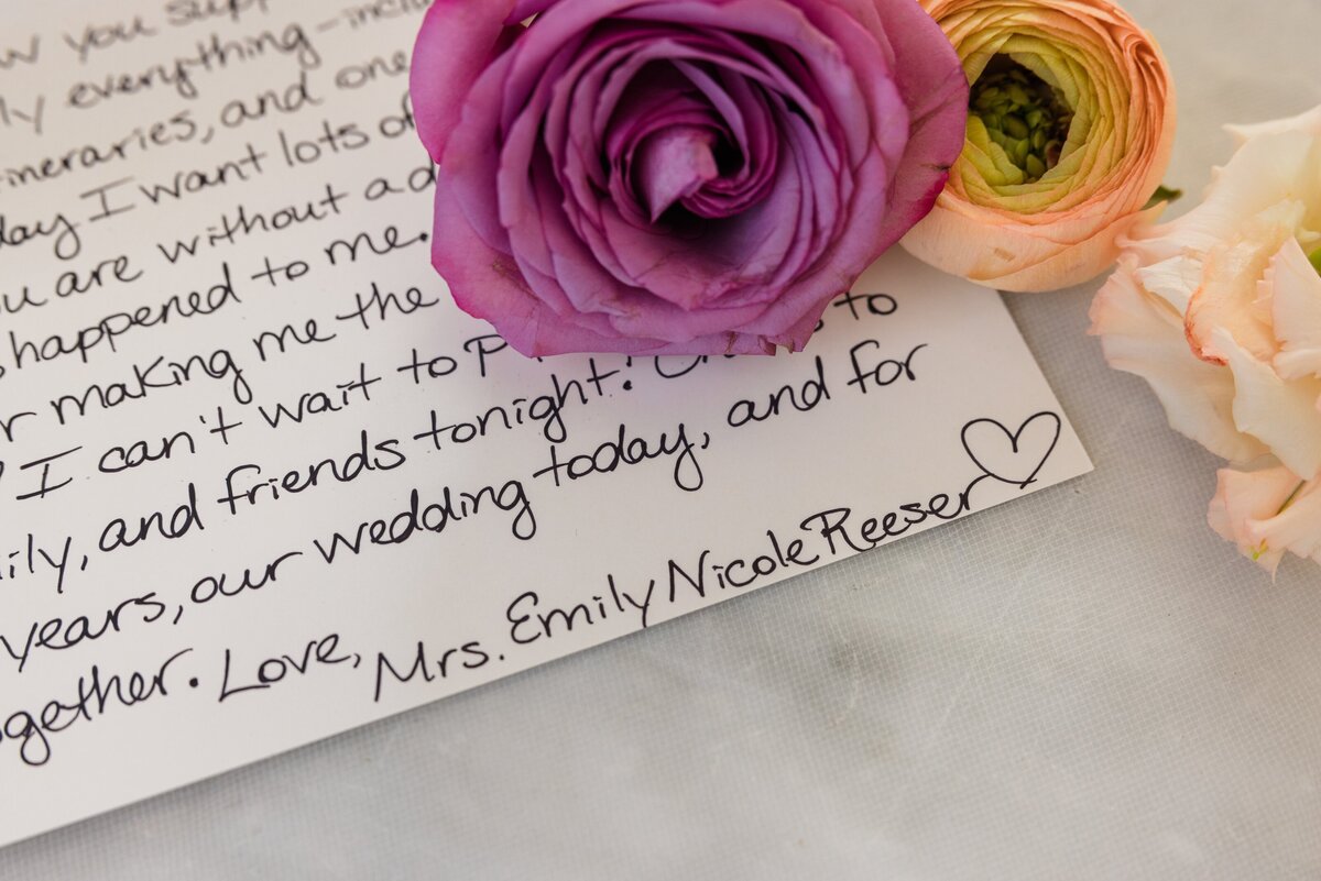 Handwritten note signed by Mrs. Emily Nicole Reeser, wedding coordinator from Iowa, surrounded by a pink, purple, and peach rose, implying a romantic context.