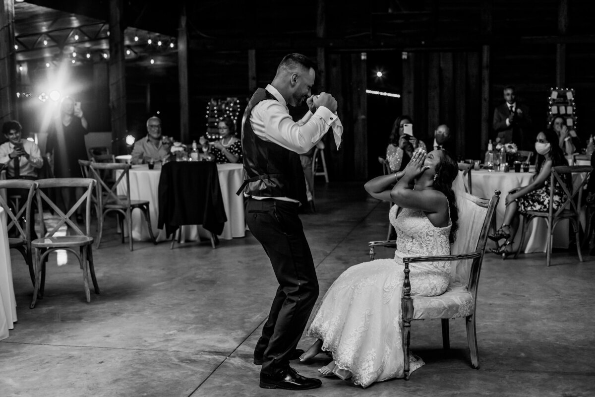 groom dancing for bride about to remove the garter at florida rustic barn weddings