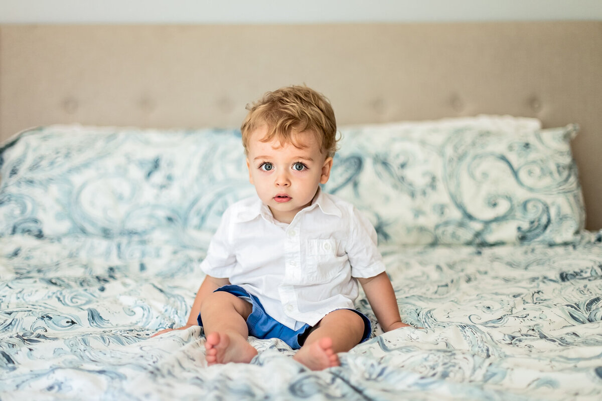 In home newborn family photo-adorable -toddler boy sitting on bed in Westfield-NJ home