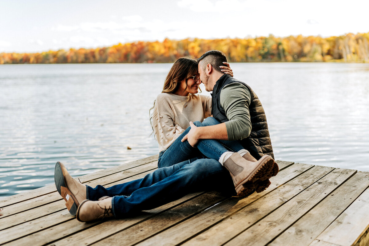 couple cuddling on dock on a lake in autumn season