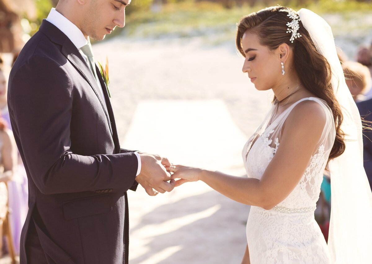 Groom putting ring on bride at wedding in Cancun