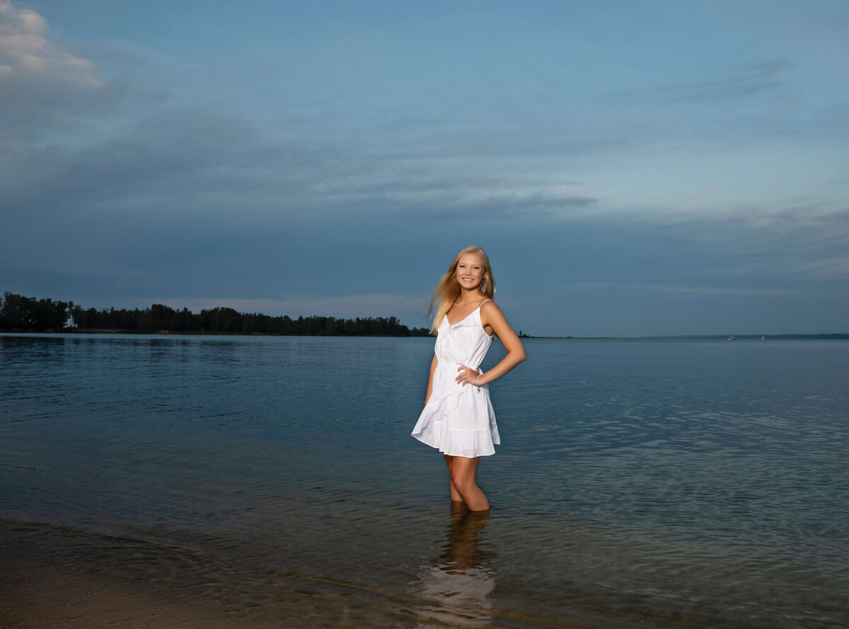 Senior photo of a girl standing in the water at an Erie Pa beach at sunset