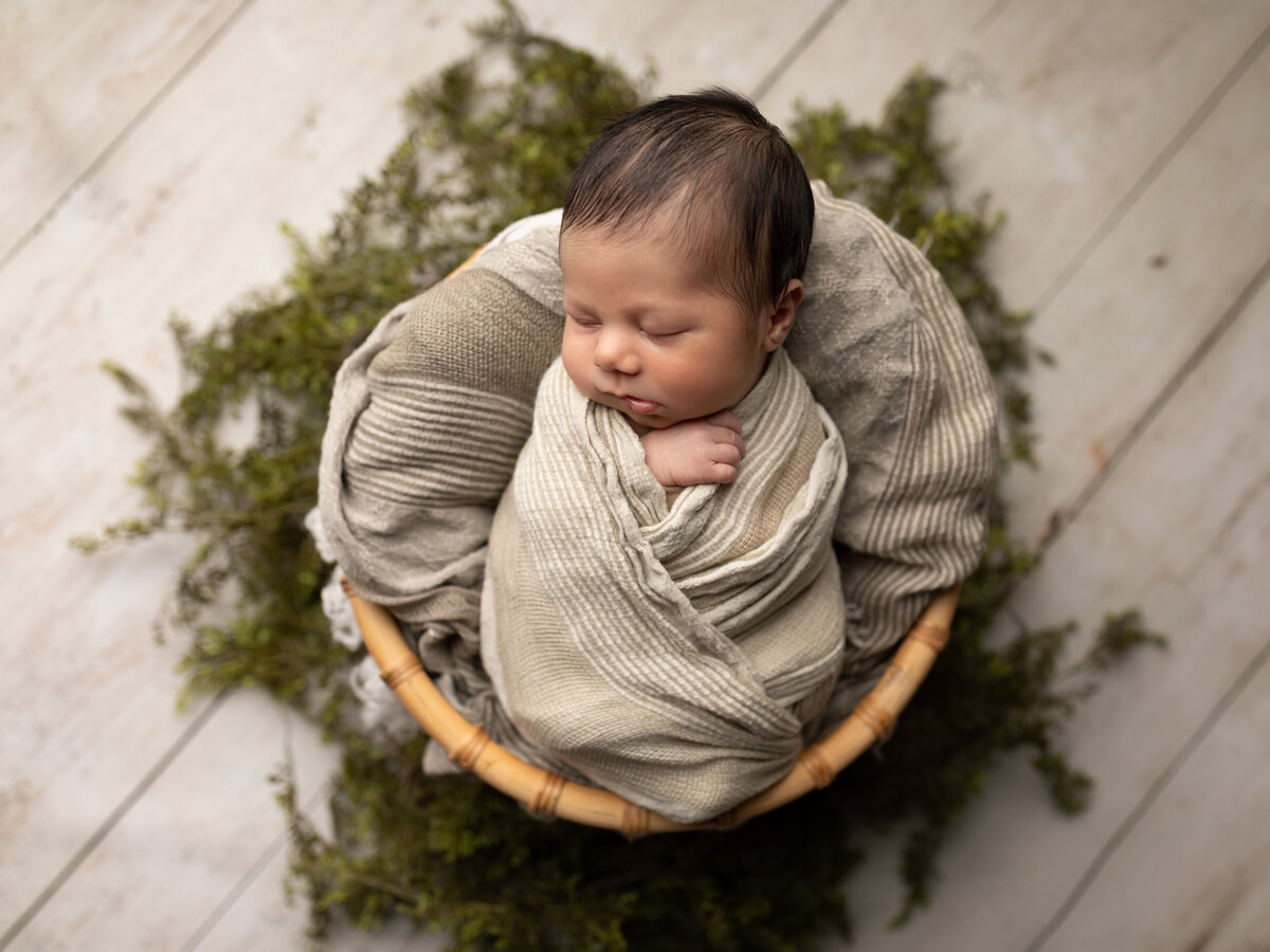 newborn baby boy wrapped in beige for studio portraits