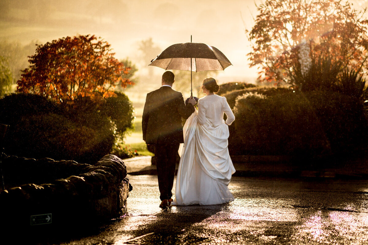 bride and groom walking with umbrella