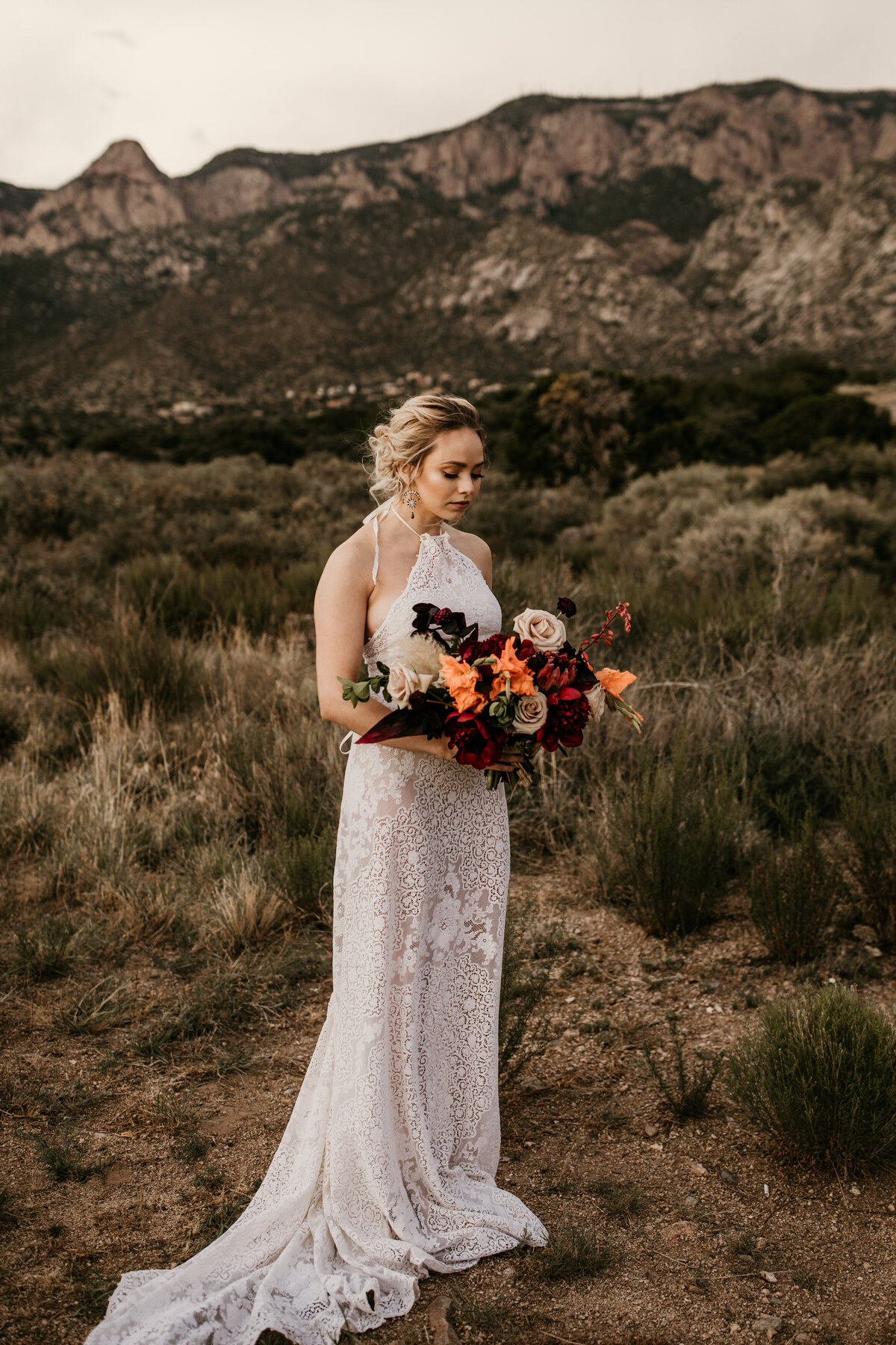 bride looking at bouquet in front of mountain